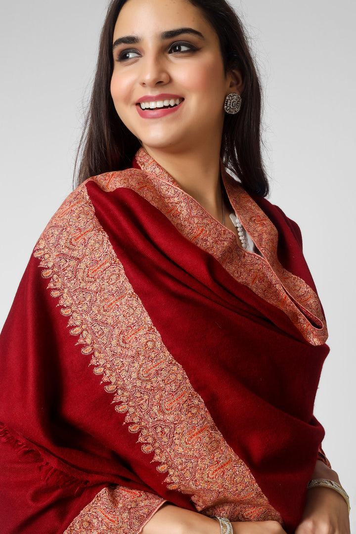 This bright maroon handmade Kashmiri pashmina shawl is made of the finest pashmina wool and has gorgeous Sozni embroidery done on all four sides in the conventional Dordaar pattern to wrap you in luxury. The shawl is enhanced by the delicate and exquisite needlework, which elevates its tradition. This bright maroon handmade Kashmiri pashmina shawl is made of the finest pashmina wool and has gorgeous Sozni embroidery done on all four sides in the conventional Dordaar pattern to wrap you in luxury. The shawl is enhanced by the delicate and exquisite needlework, which elevates its tradition.