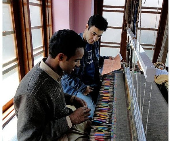 Artisans at Kepra hand-weaving on a traditional loom, discussing Pashmina design and colour implementation.