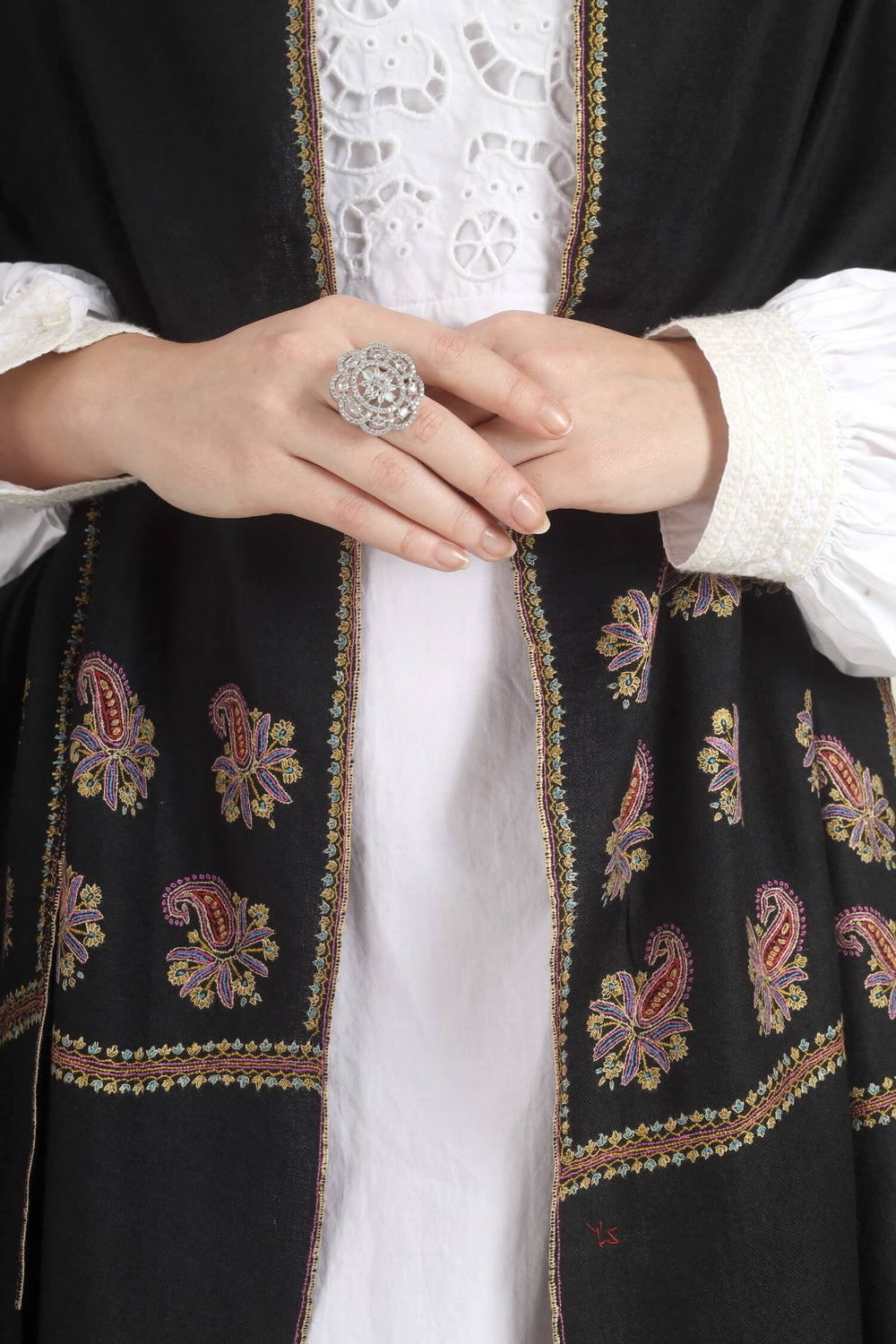Model wearing a black GI Kashmiri Pure Pashmina stole with multicolour paisley Sozni embroidery on the borders over a white outfit.