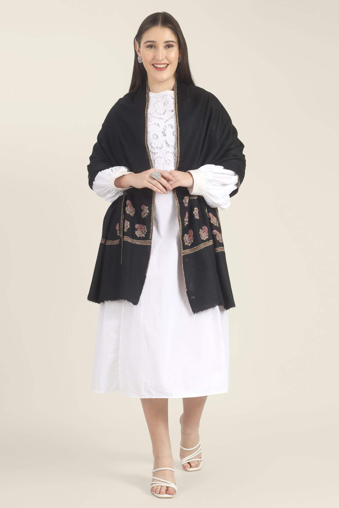 Model wearing a black GI Kashmiri Pure Pashmina stole with multicolour paisley Sozni embroidery on the borders over a white outfit.