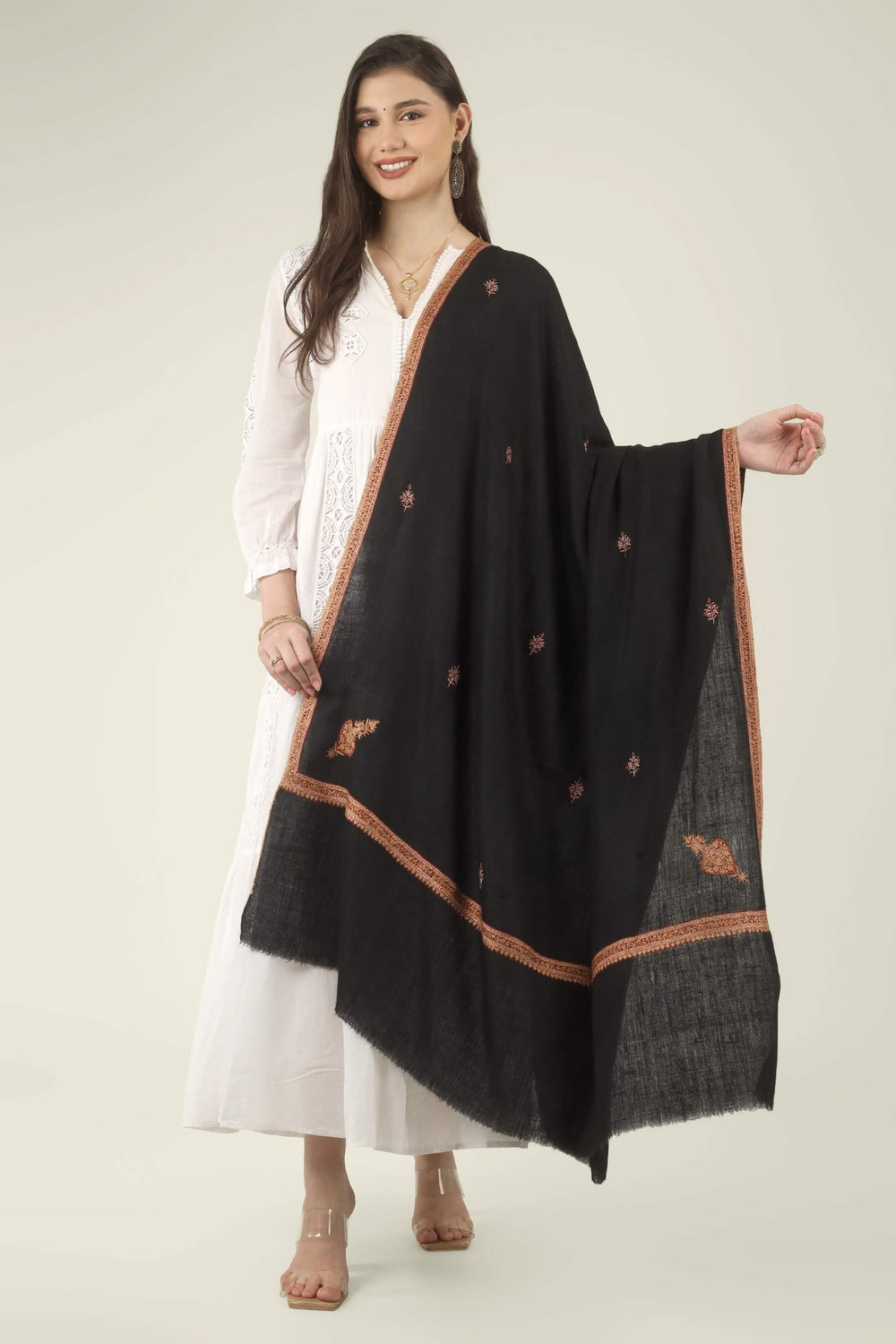 This Black GI Kashmiri Pure Pashmina Hashidaar Embroidered Shawl features a deep, solid black body framed by a richly worked border in copper, rust and soft pink, with small floral buti motifs scattered across the ground.