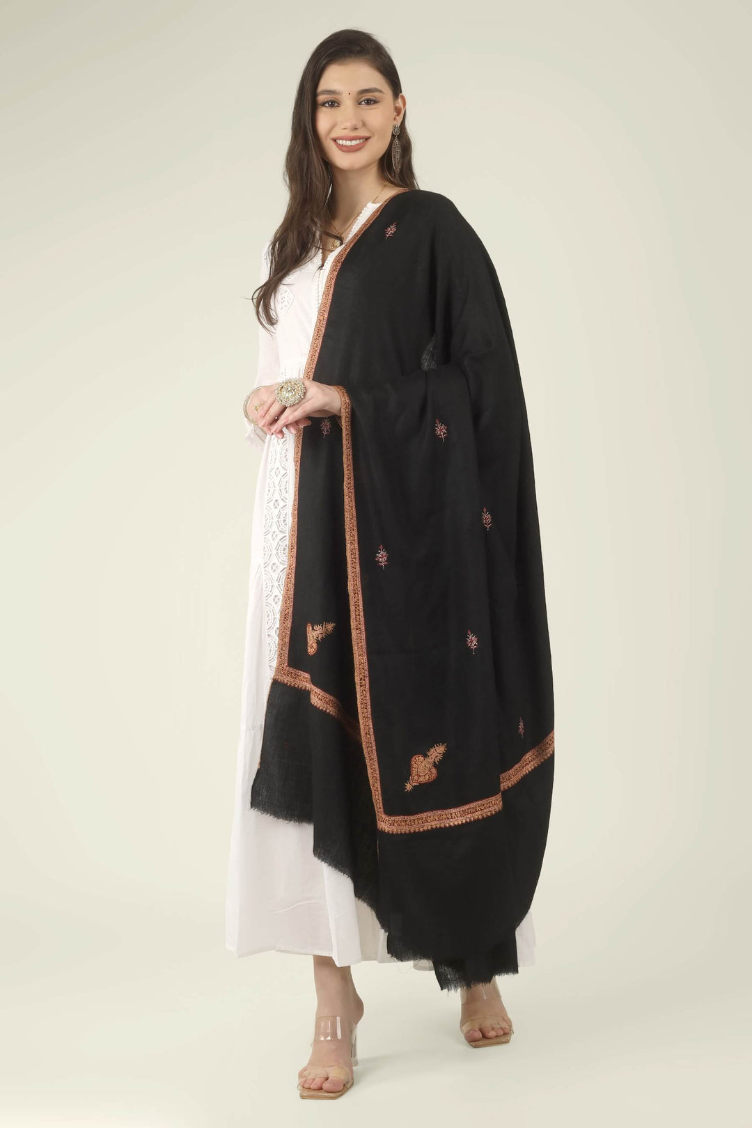 This Black GI Kashmiri Pure Pashmina Hashidaar Embroidered Shawl features a deep, solid black body framed by a richly worked border in copper, rust and soft pink, with small floral buti motifs scattered across the ground.
