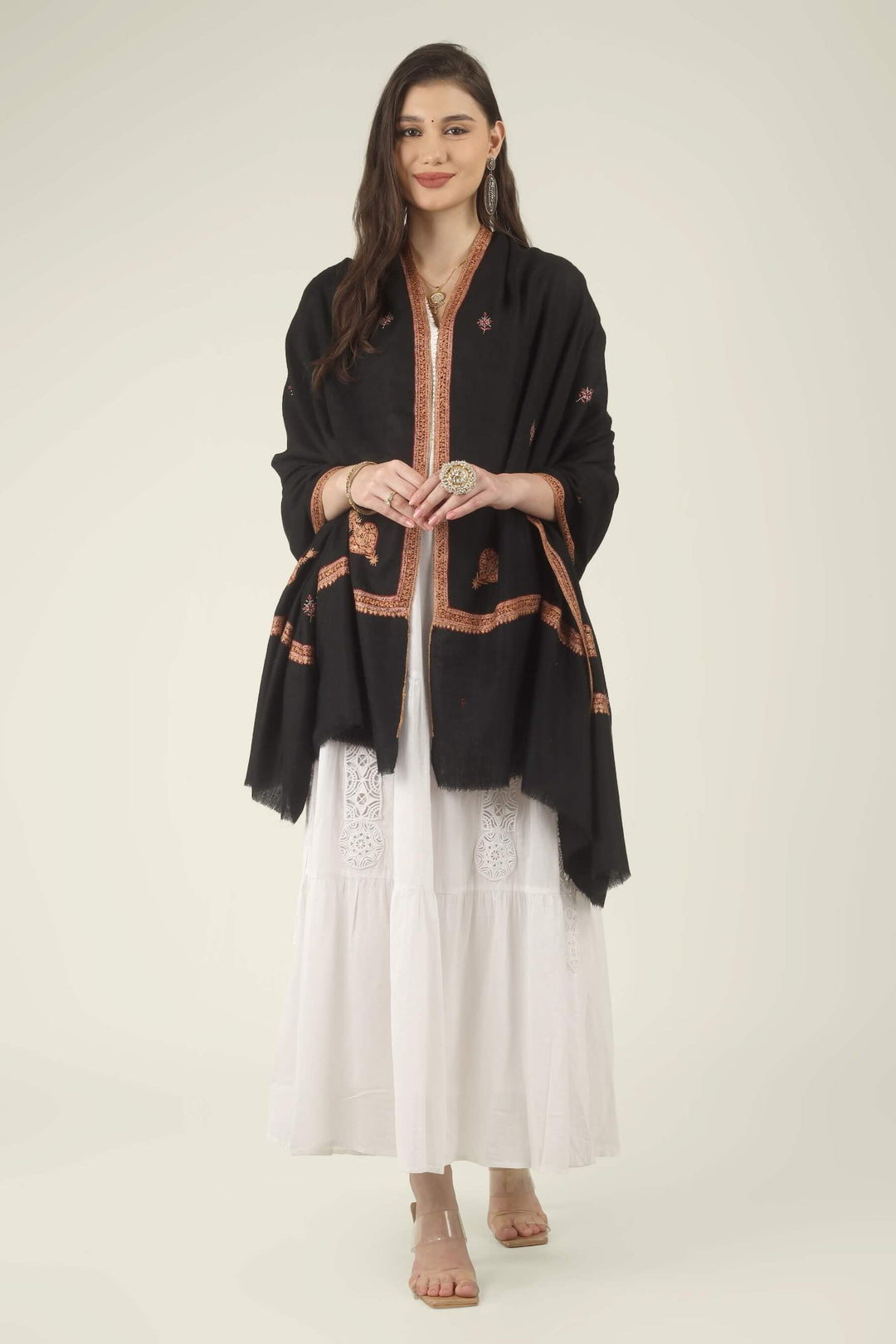 This Black GI Kashmiri Pure Pashmina Hashidaar Embroidered Shawl features a deep, solid black body framed by a richly worked border in copper, rust and soft pink, with small floral buti motifs scattered across the ground.