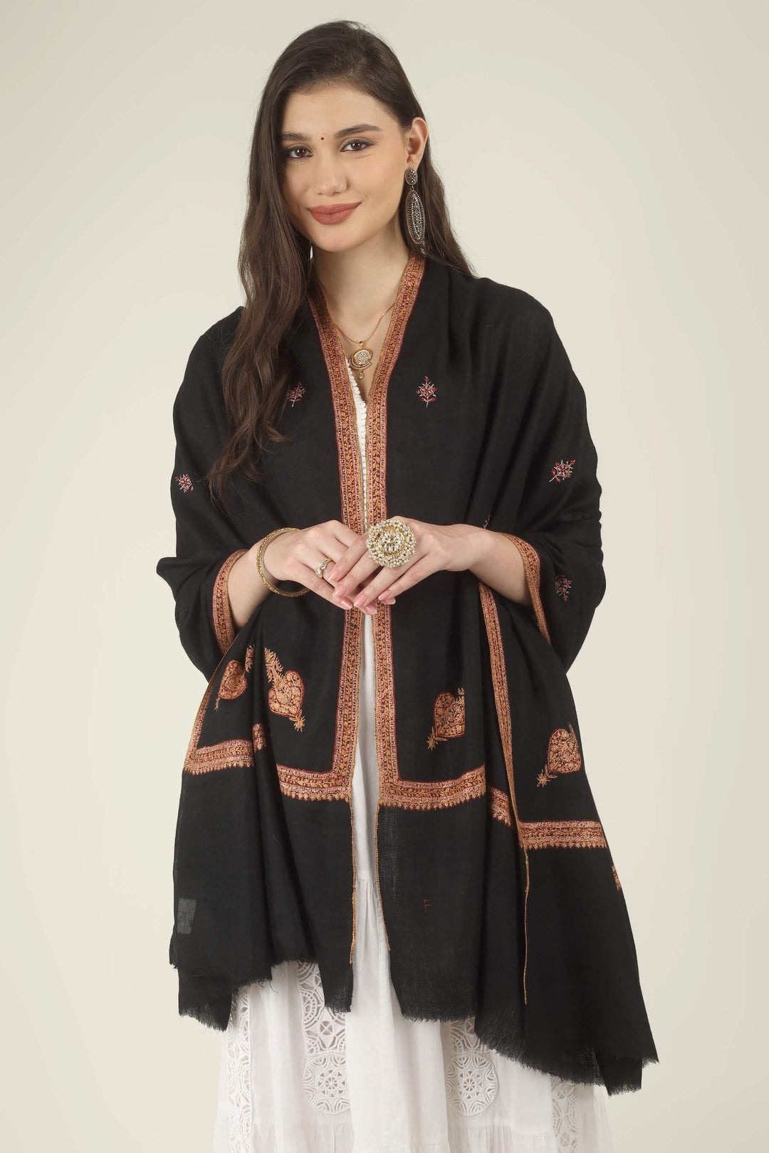 This Black GI Kashmiri Pure Pashmina Hashidaar Embroidered Shawl features a deep, solid black body framed by a richly worked border in copper, rust and soft pink, with small floral buti motifs scattered across the ground.