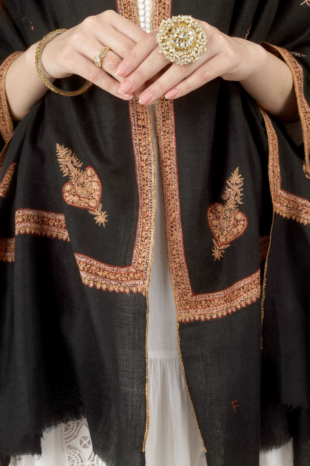 This Black GI Kashmiri Pure Pashmina Hashidaar Embroidered Shawl features a deep, solid black body framed by a richly worked border in copper, rust and soft pink, with small floral buti motifs scattered across the ground.