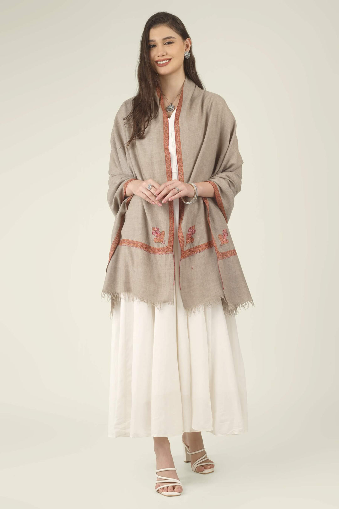 This Natural Khudrang GI Kashmiri Pure Pashmina Border Embroidered Shawl features a beautifully textured, undyed oatmeal-beige body. It is elegantly framed by continuous, richly worked red and orange borders