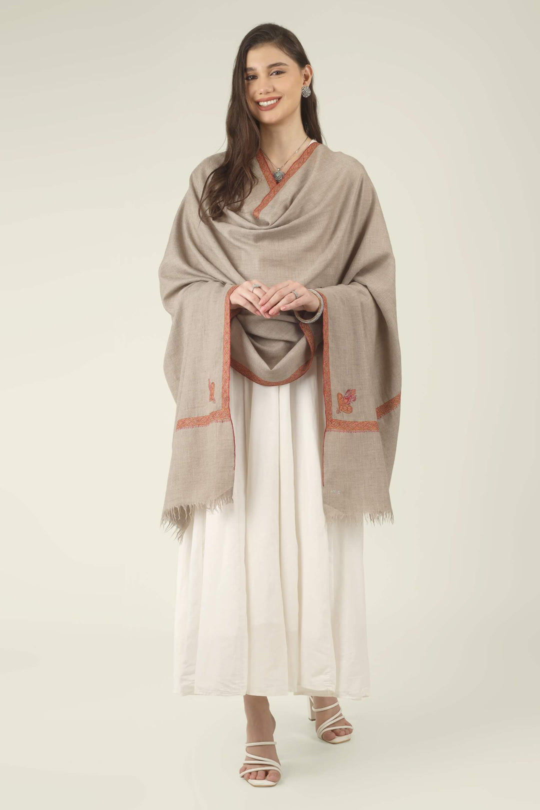 This Natural Khudrang GI Kashmiri Pure Pashmina Border Embroidered Shawl features a beautifully textured, undyed oatmeal-beige body. It is elegantly framed by continuous, richly worked red and orange borders