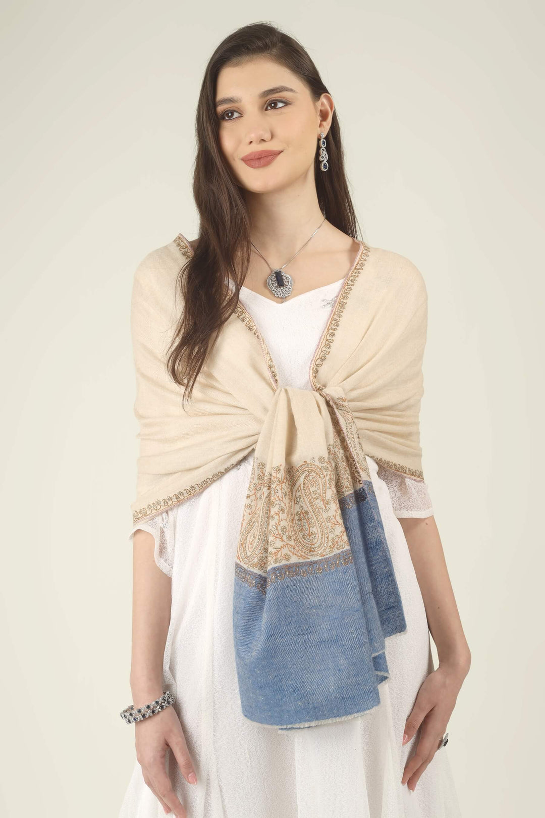 This Cream GI Kashmiri Pure Pashmina Paisley Embroidered Stole features a soft ivory-cream body with a richly worked paisley border and a contrasting panel of denim blue at the ends.