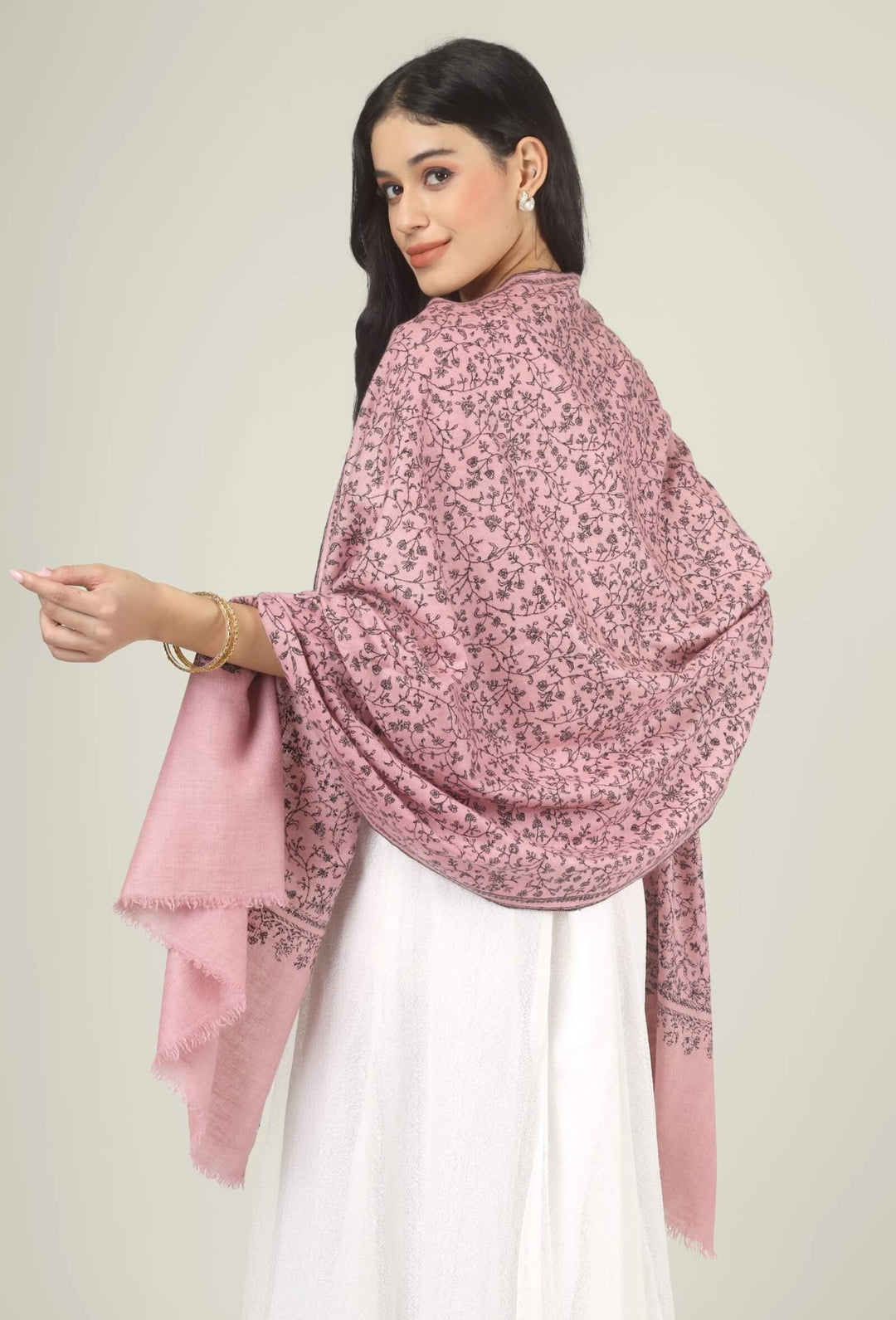 Model wearing a pink GI Kashmiri Pure Pashmina stole with all-over charcoal floral jaal Sozni embroidery over a white dress.