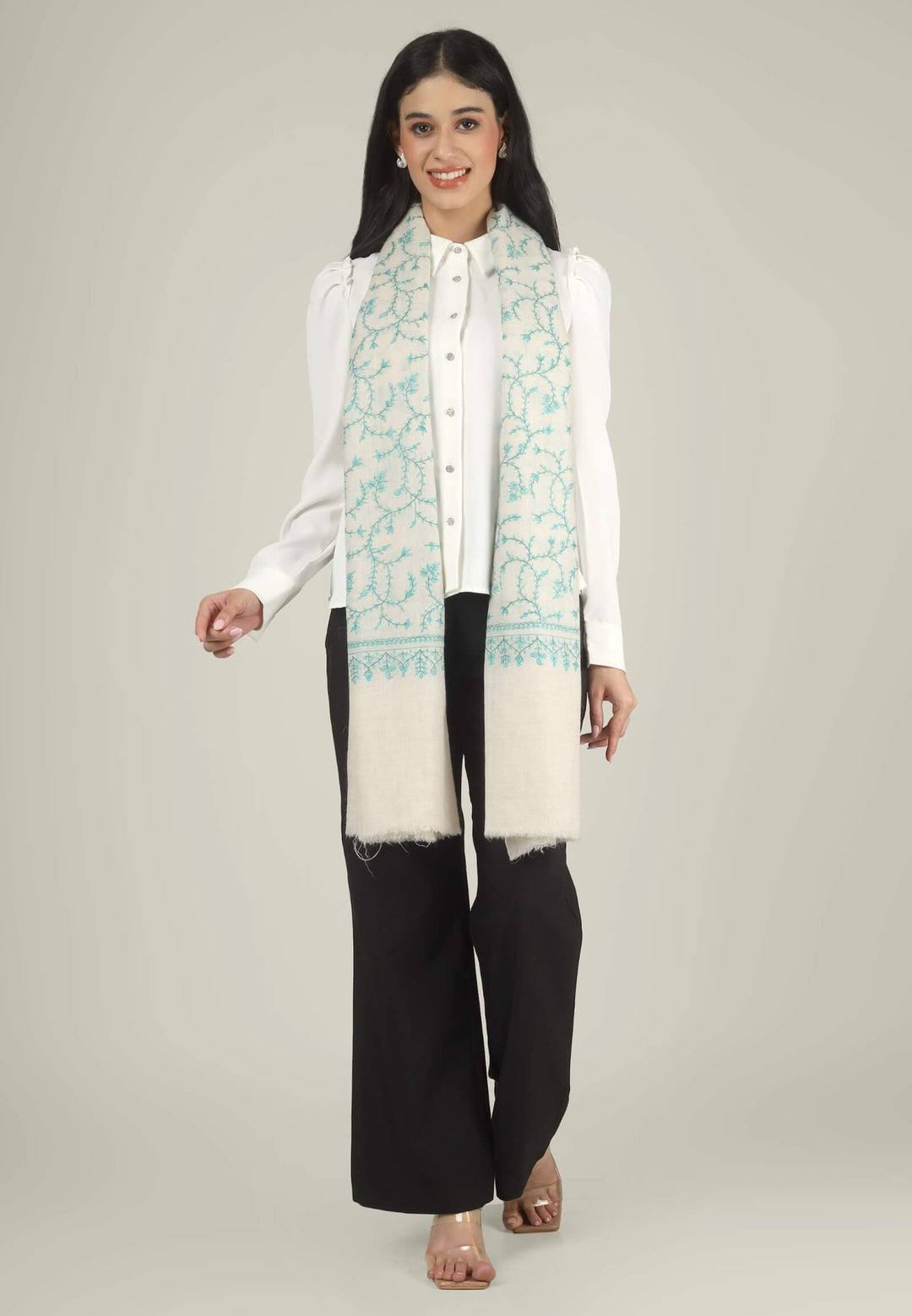 Close-up of a white GI Kashmiri Pure Pashmina stole with turquoise-green floral jaal Sozni embroidery knotted at the front over a white shirt.