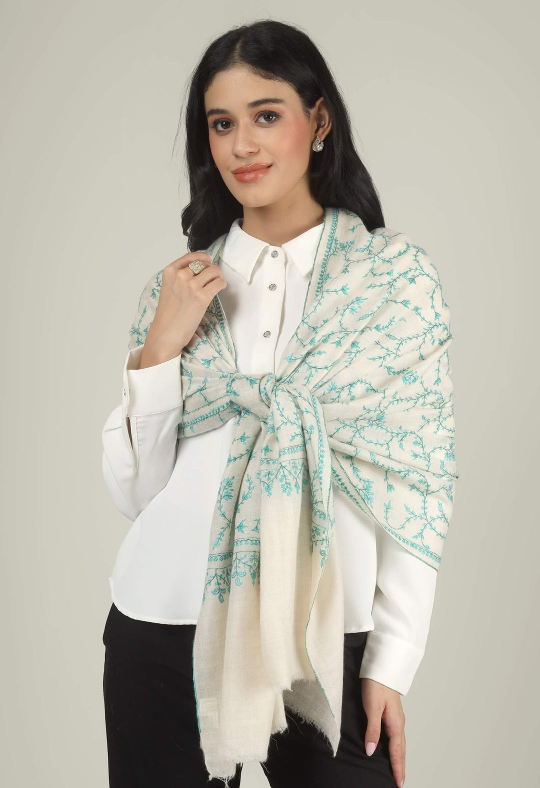 Close-up of a white GI Kashmiri Pure Pashmina stole with turquoise-green floral jaal Sozni embroidery knotted at the front over a white shirt.