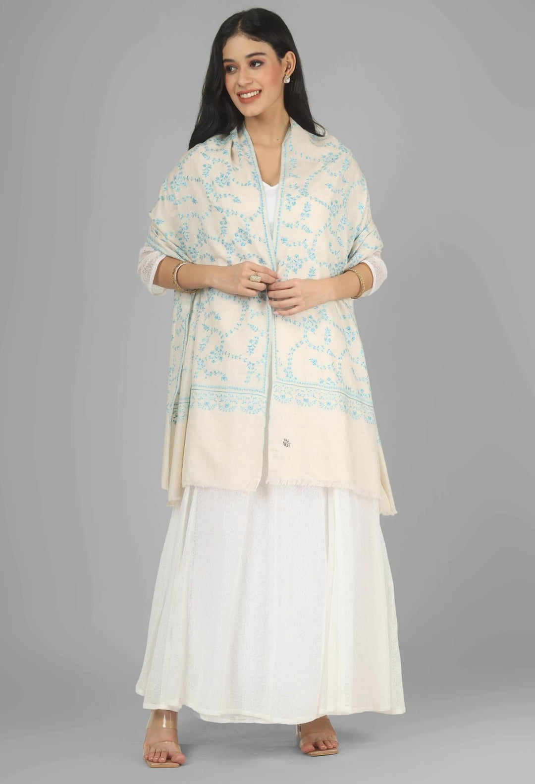 Close-up of a white GI Kashmiri Pure Pashmina stole with delicate sky-blue floral Sozni embroidery draped around the neck.
