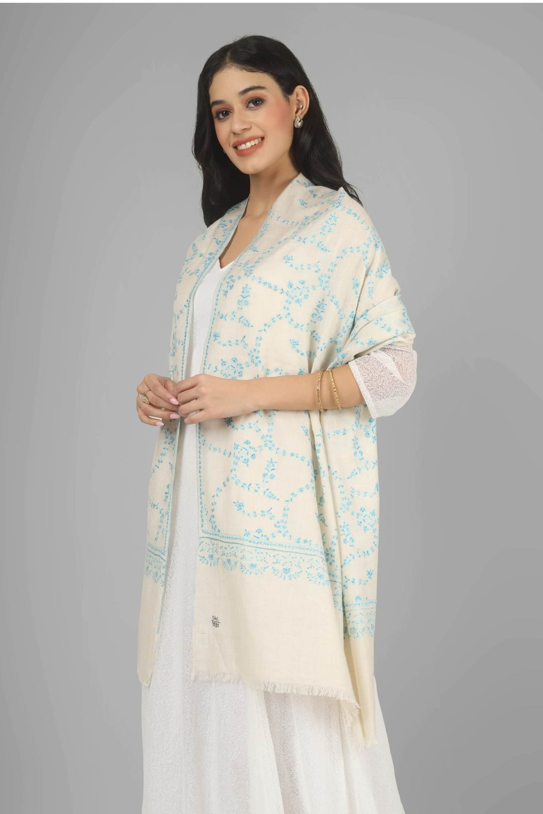 Close-up of a white GI Kashmiri Pure Pashmina stole with delicate sky-blue floral Sozni embroidery draped around the neck.