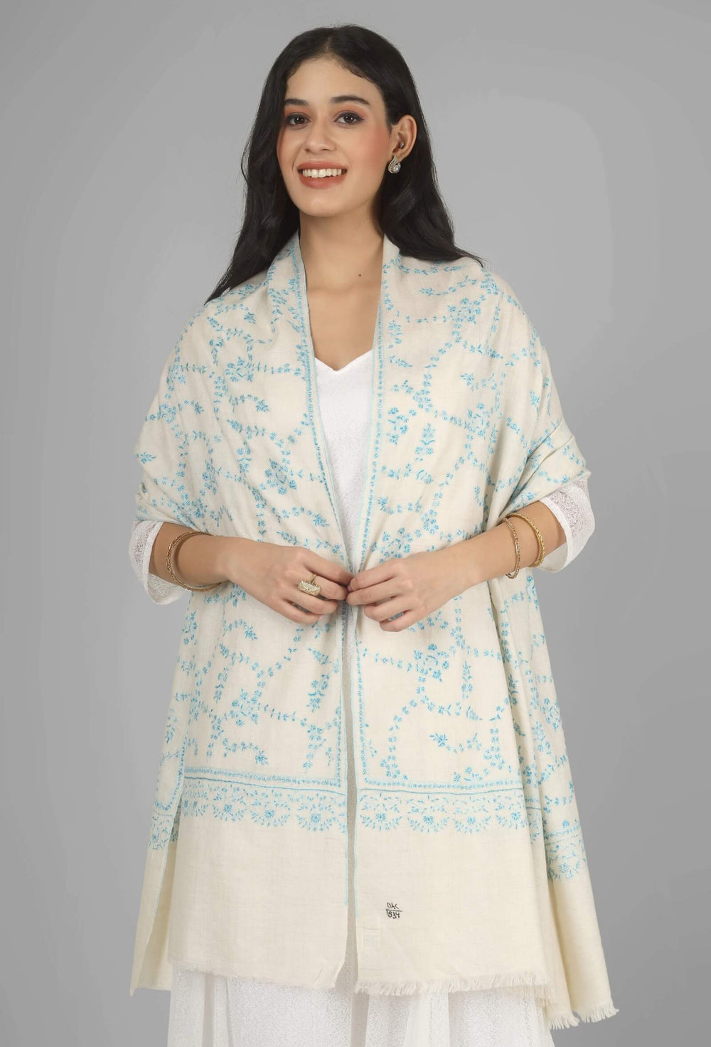 Close-up of a white GI Kashmiri Pure Pashmina stole with delicate sky-blue floral Sozni embroidery draped around the neck.