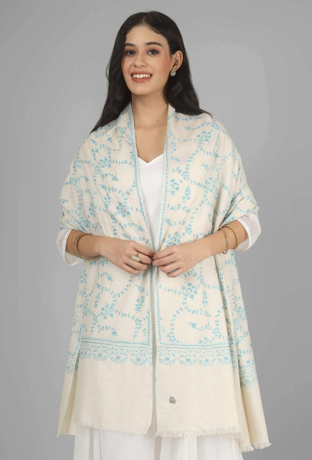 Close-up of a white GI Kashmiri Pure Pashmina stole with delicate sky-blue floral Sozni embroidery draped around the neck.