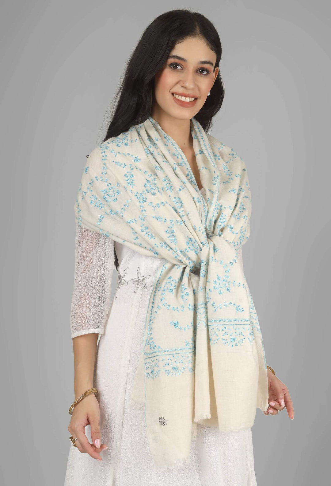 Close-up of a white GI Kashmiri Pure Pashmina stole with delicate sky-blue floral Sozni embroidery draped around the neck.