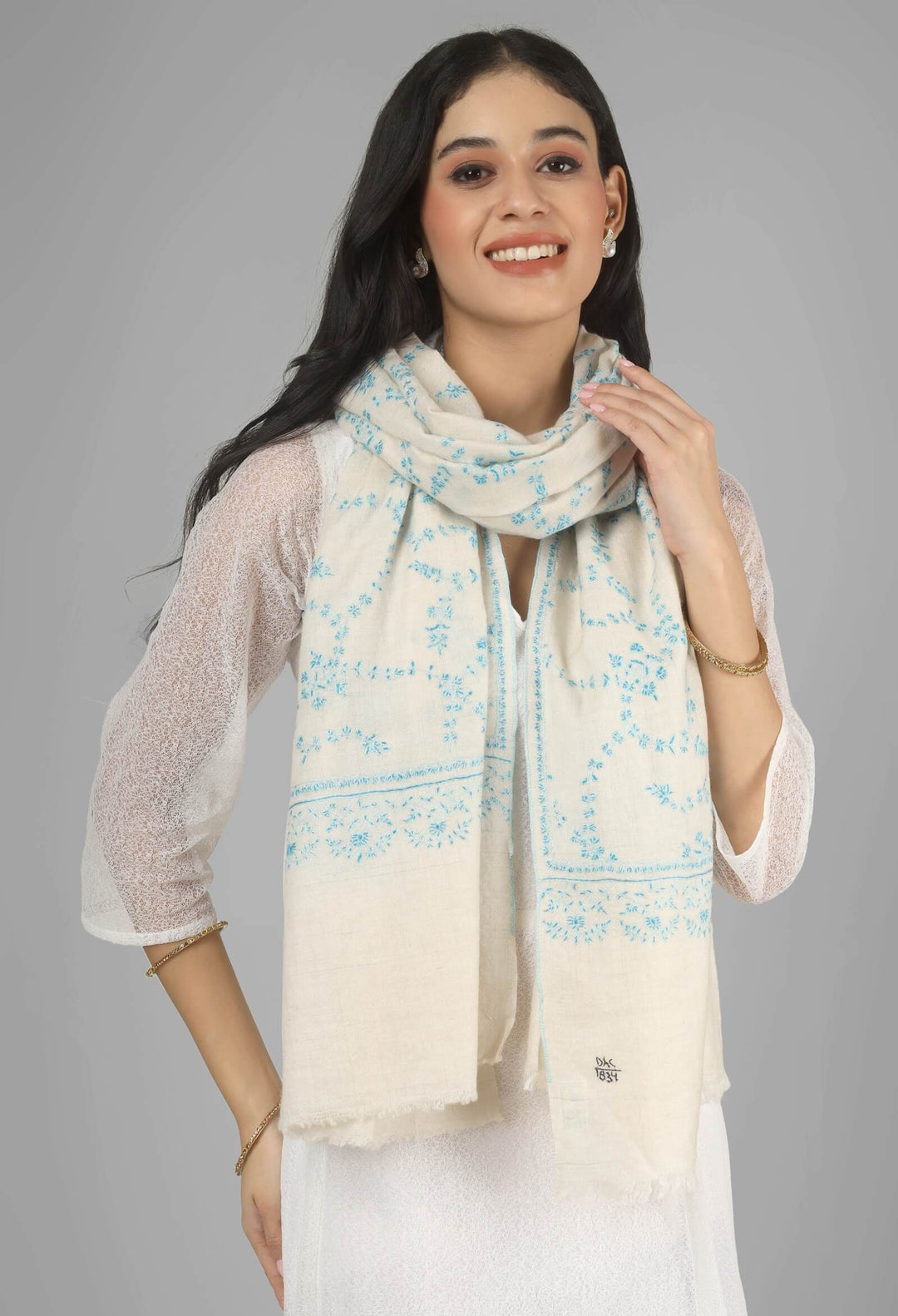 Close-up of a white GI Kashmiri Pure Pashmina stole with delicate sky-blue floral Sozni embroidery draped around the neck.