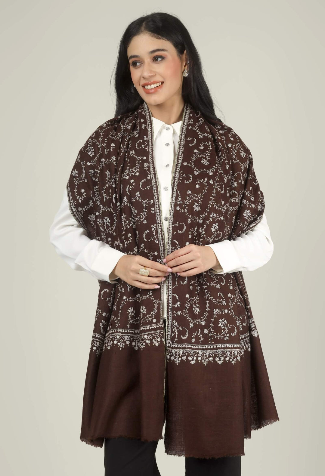 Close-up of a brown GI Kashmiri Pure Pashmina stole with ivory floral jaal and paisley Sozni embroidery worn open over a white shirt.