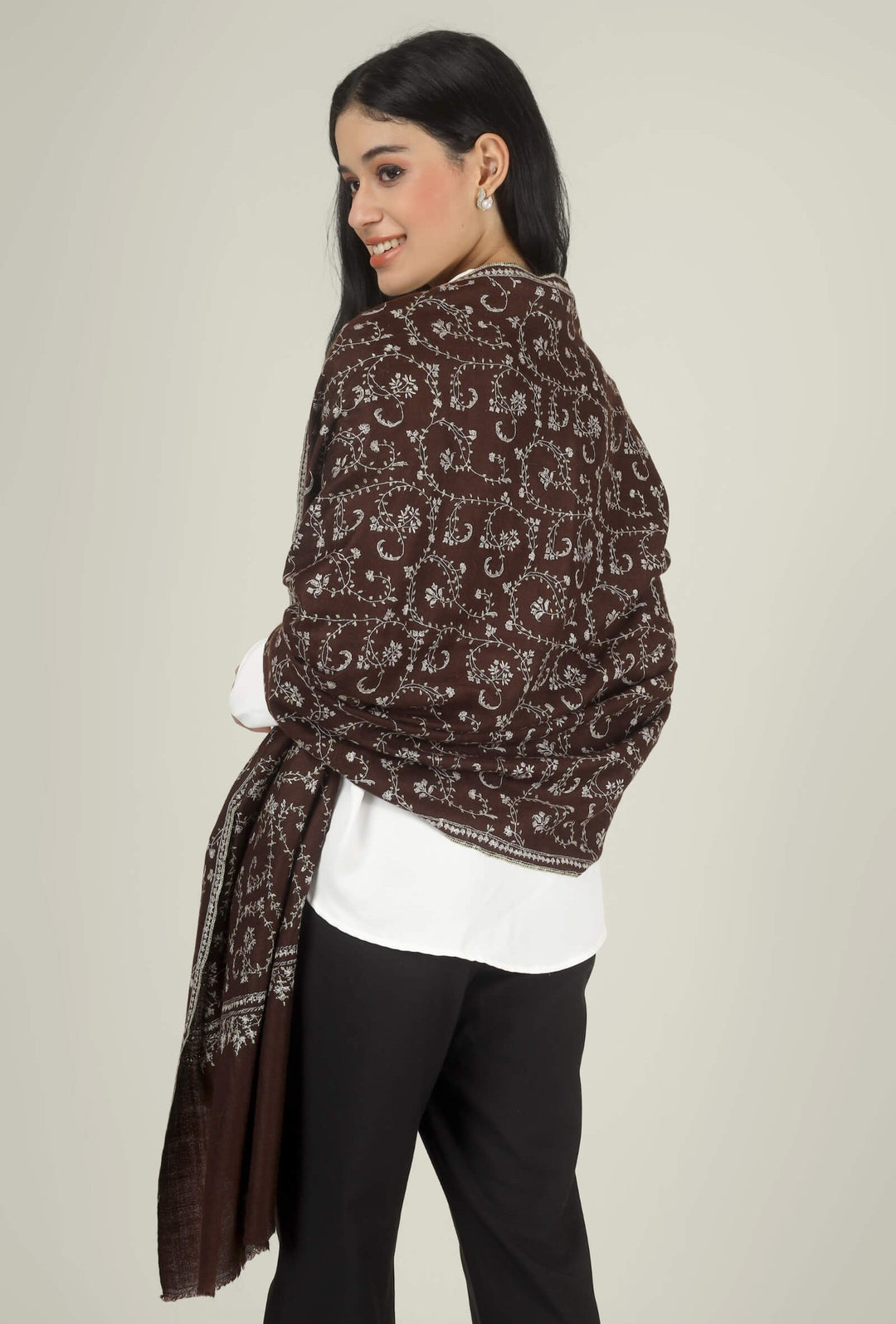 Close-up of a brown GI Kashmiri Pure Pashmina stole with ivory floral jaal and paisley Sozni embroidery worn open over a white shirt.