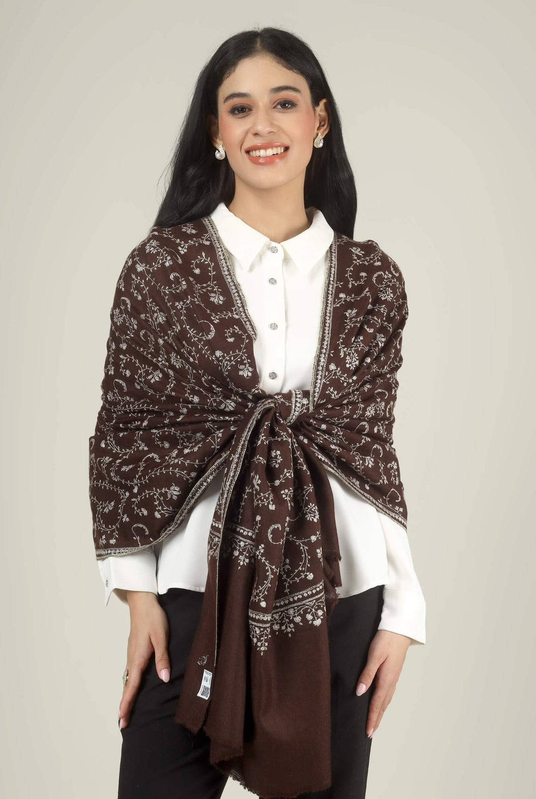 Close-up of a brown GI Kashmiri Pure Pashmina stole with ivory floral jaal and paisley Sozni embroidery worn open over a white shirt.