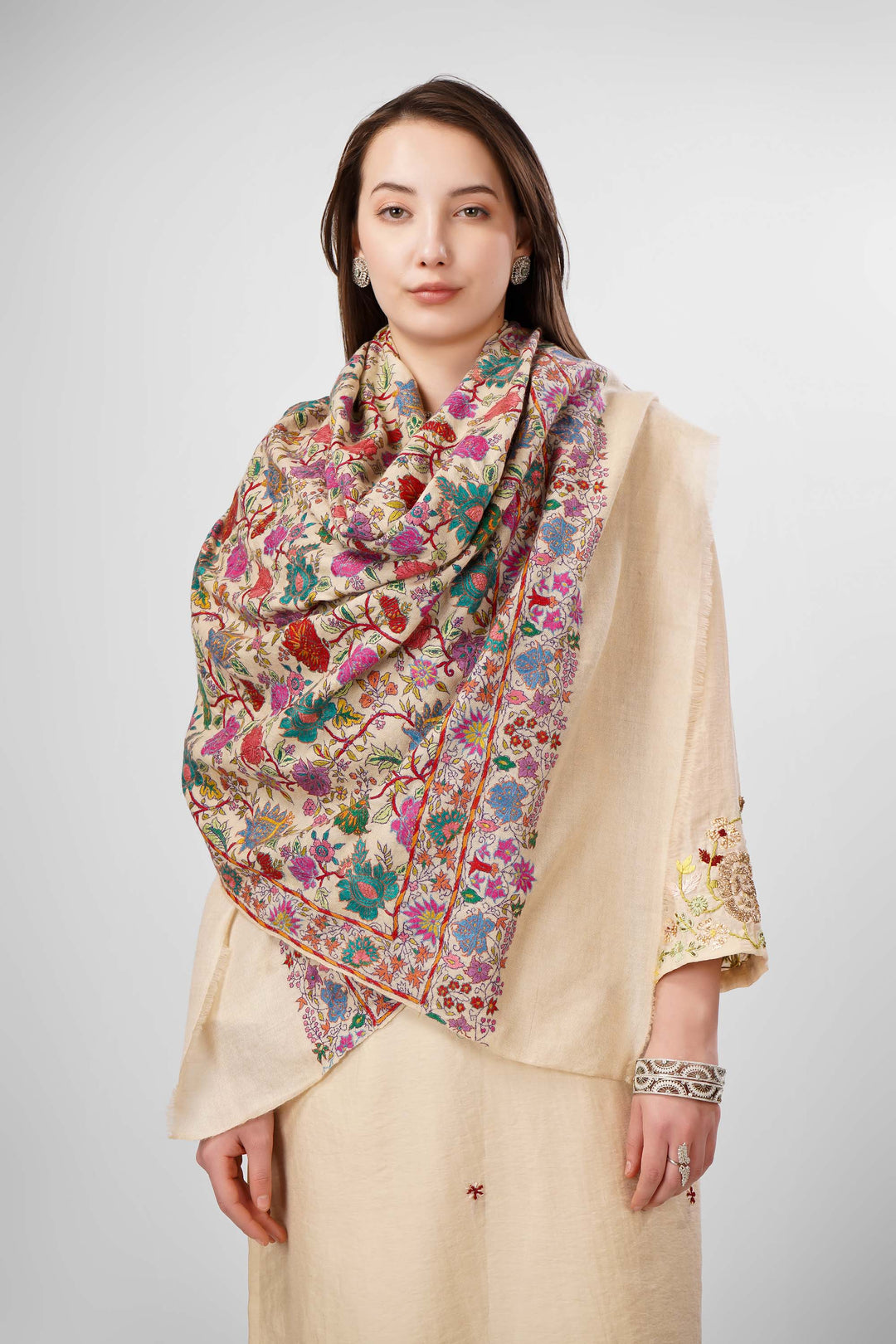 White Sozni Jama Pashmina Shawls Online – Artistry in Multicolor Floral Finesse
   The Pashmina White Sozni Malaika Ruqaiya Jama Shawl is a dazzling instance of Kashmiri handwoven royalty. Spun from premium pure pashmina, this shawl features a pristine ivory-white base enveloped in flamboyant allover sozni embroidery