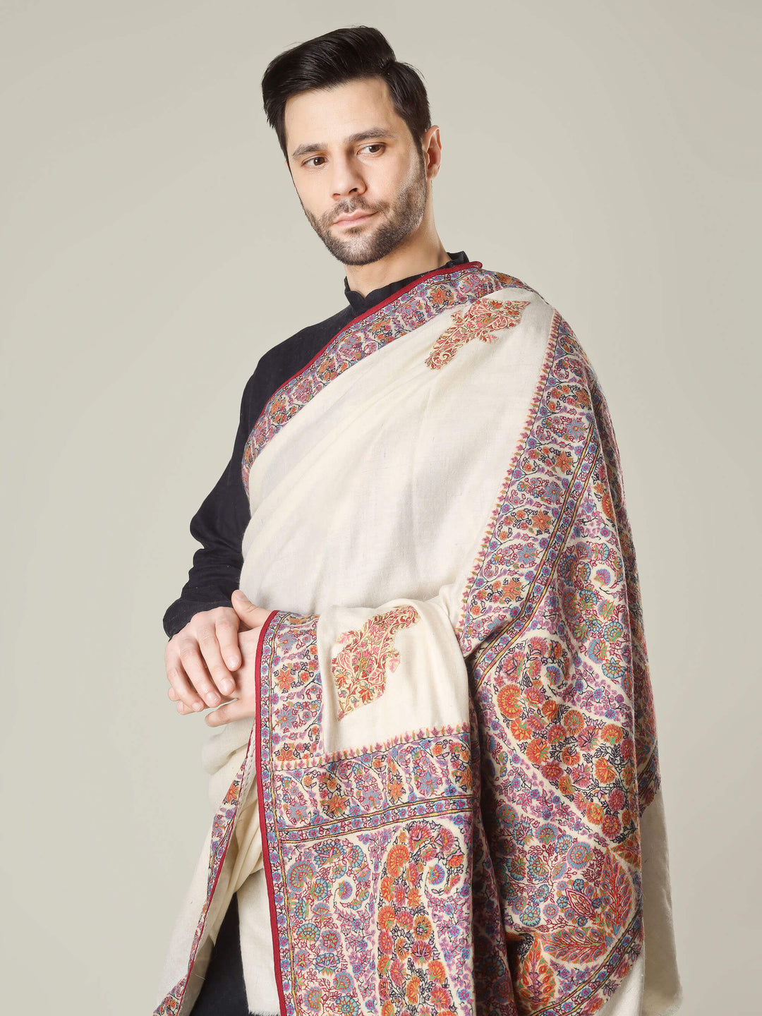 Antique Kashmiri kalamkari sozni men’s shawl with intricate multicolour paisley and floral embroidery on ivory pashmina, draped over a black kurta, handcrafted luxury wedding shawl from Kashmir.