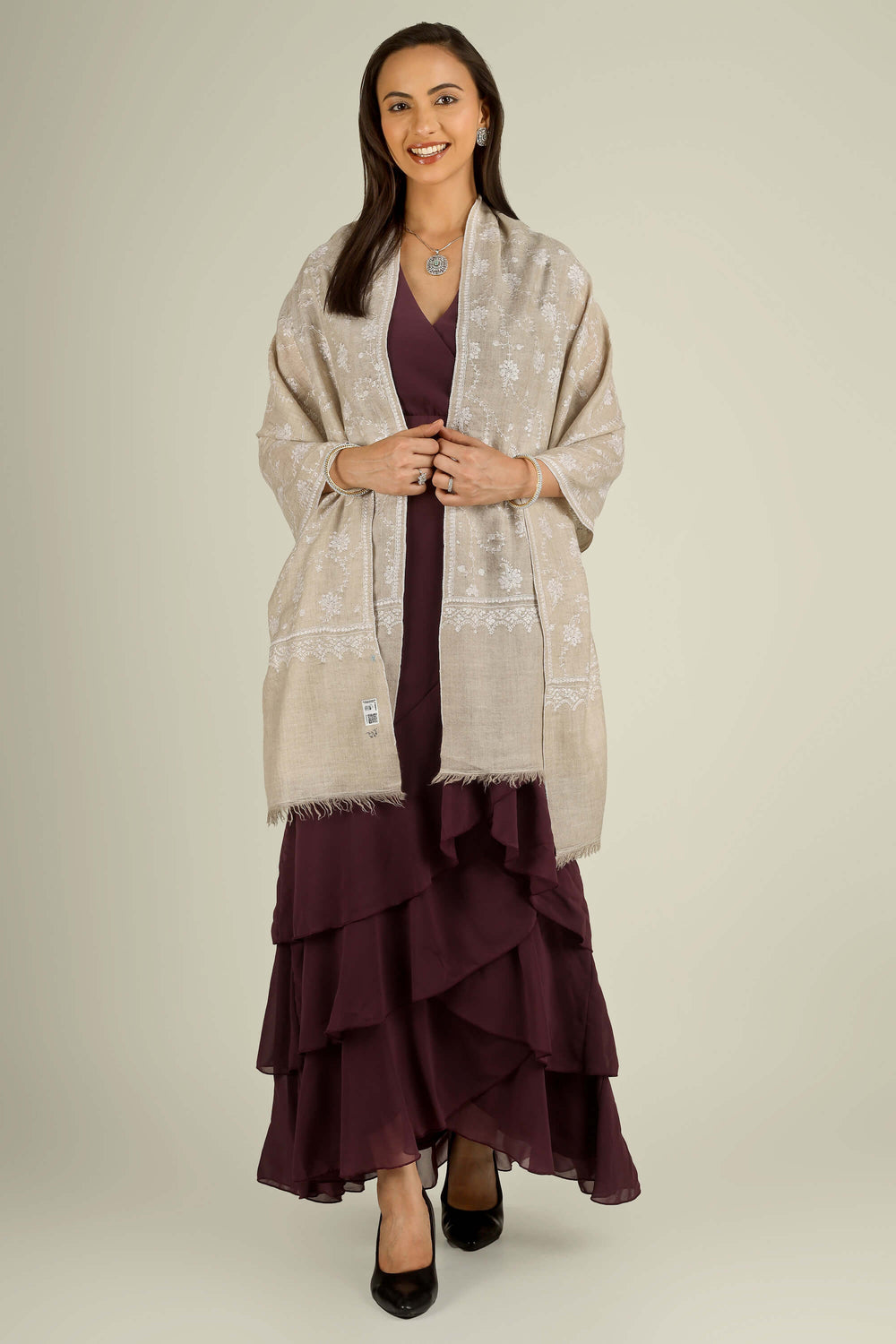 Beige GI Kashmiri pure pashmina embroidered stole by Kepra, draped on smiling model over plum dress, front view for Vienna winter styling
