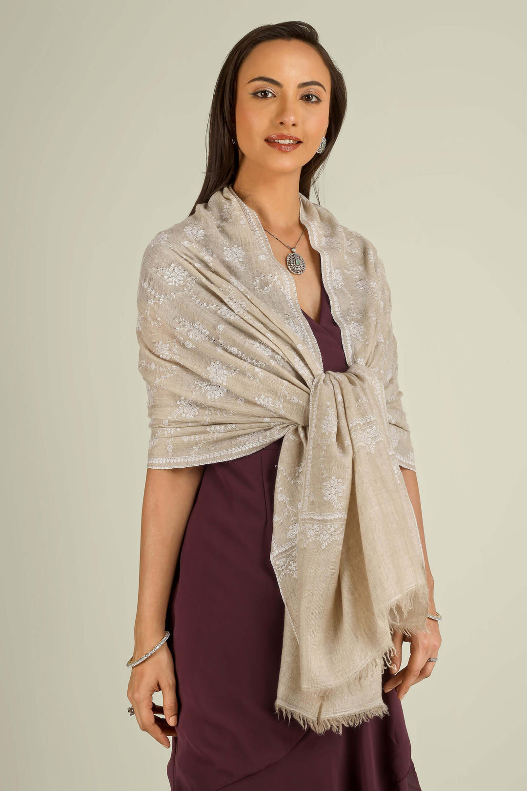 Beige GI Kashmiri pure pashmina embroidered stole by Kepra, draped on smiling model over plum dress, front view for Vienna winter styling