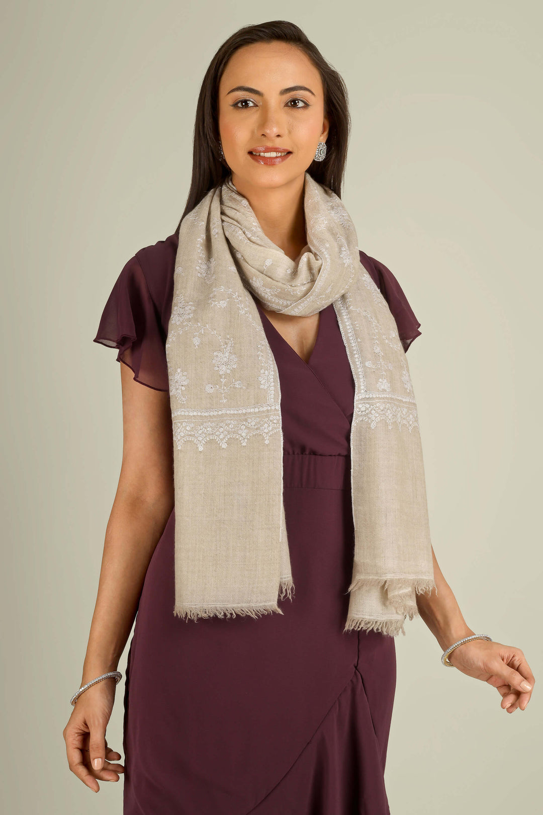 Beige GI Kashmiri pure pashmina embroidered stole by Kepra, draped on smiling model over plum dress, front view for Vienna winter styling