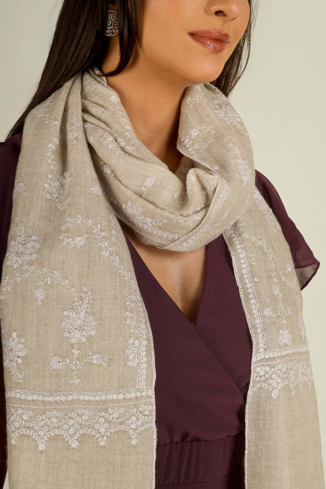 Beige GI Kashmiri pure pashmina embroidered stole by Kepra, draped on smiling model over plum dress, front view for Vienna winter styling