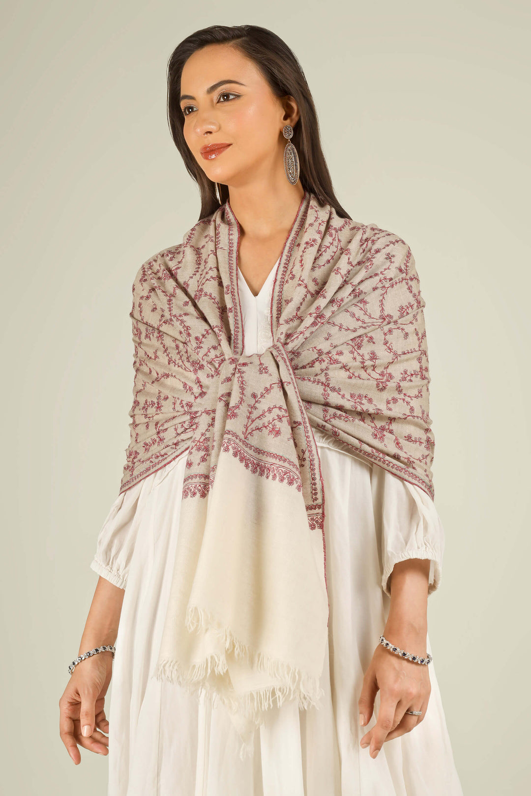 Close-up of beige Kashmiri pure pashmina stole with red sozni vine embroidery, held at the front, detail view for Berlin winter styling