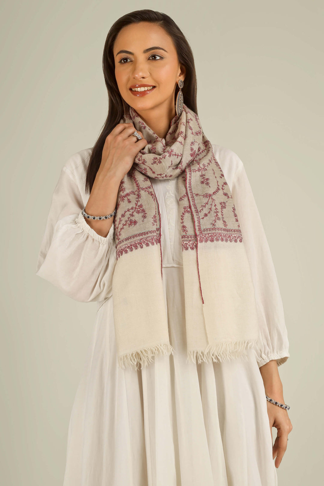 Close-up of beige Kashmiri pure pashmina stole with red sozni vine embroidery, held at the front, detail view for Berlin winter styling