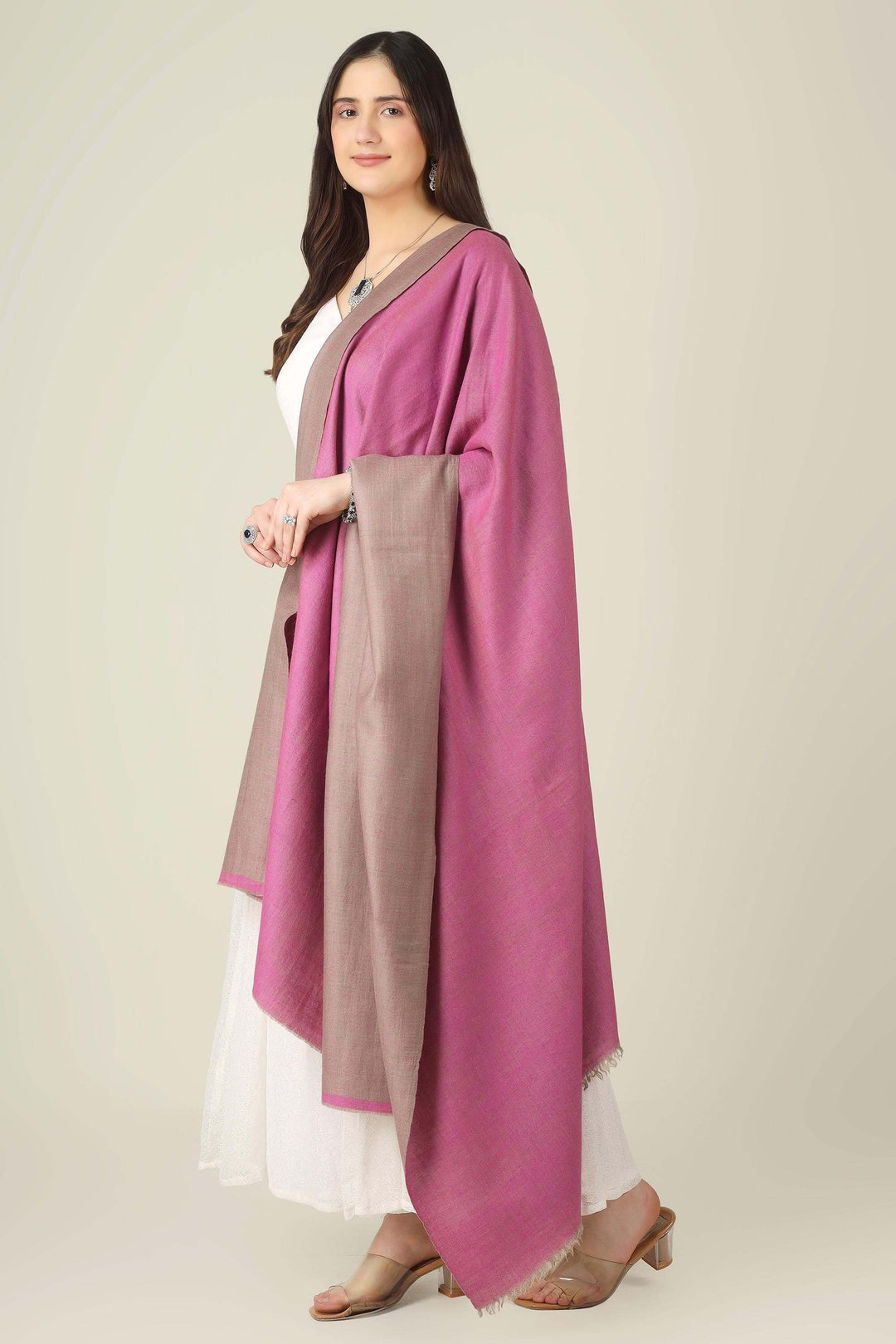 This reversible pashmina shawl pairs a sophisticated dusty taupe with a vibrant fuchsia pink, giving you two distinct looks in one luxurious wrap. 