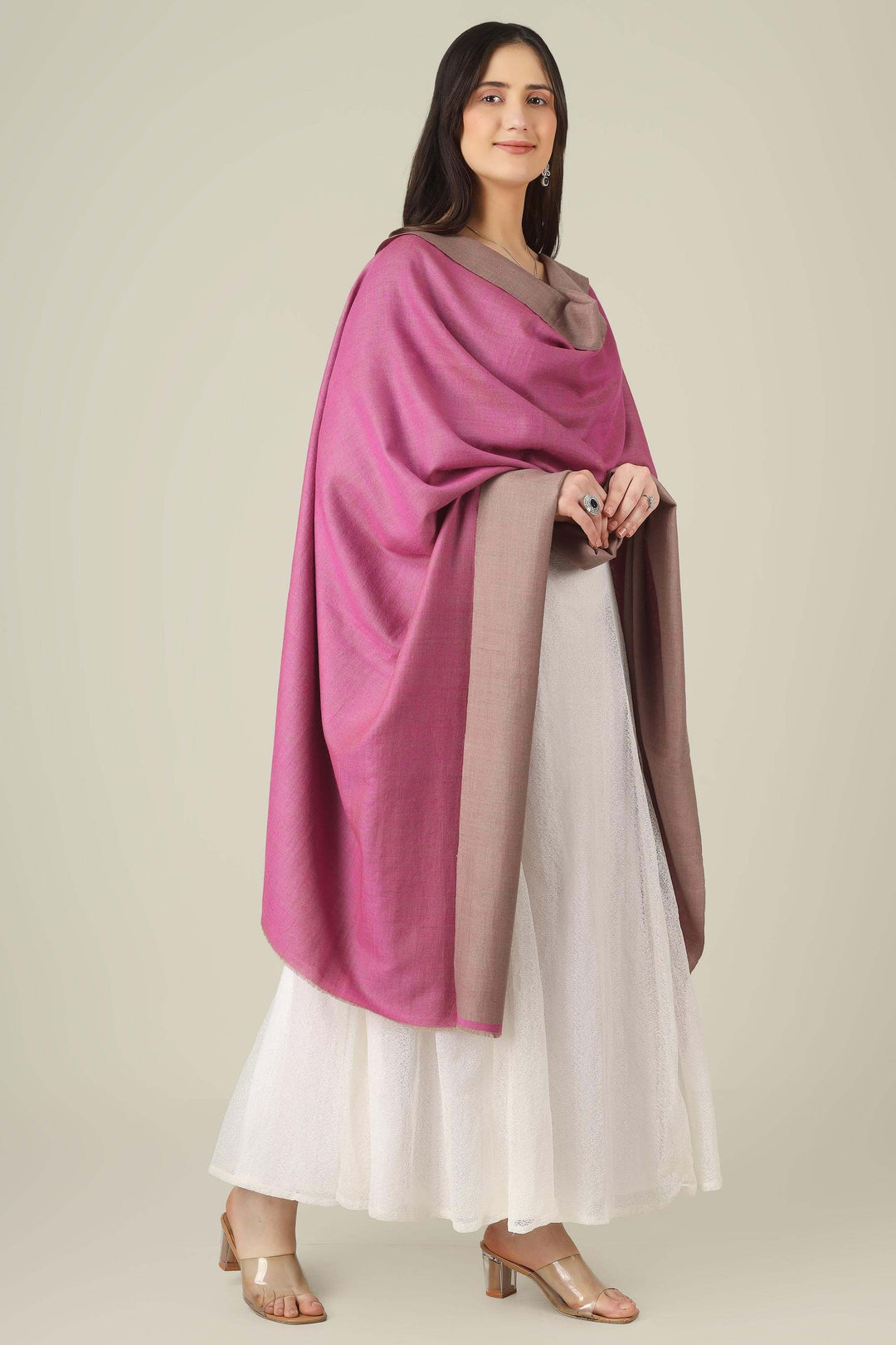 This reversible pashmina shawl pairs a sophisticated dusty taupe with a vibrant fuchsia pink, giving you two distinct looks in one luxurious wrap. 