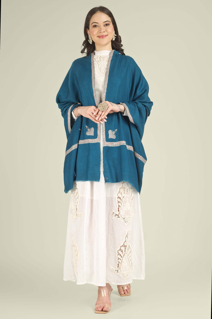 A woman modeling a teal blue shawl with silver embroidered details over a white embroidered dress, standing against a solid light beige background.
    
      | pashmina shawls online | authentic Kashmiri pashmina shawl online | pure pashmina shawl online | original GI certified pashmina shawl online | luxury men's pashmina shawl online from Kashmir | where to buy online pure pashmina in India
    
    | GI Tag Certified - Government-verified authentic Kashmiri Pashmina
    | G20 Official Partner - Selected by India for G20 Summit gifting
    | Handicraft Registered - Official recognition of traditional craftsmanship
    | Certificate of Authenticity - Every purchase includes GI certification