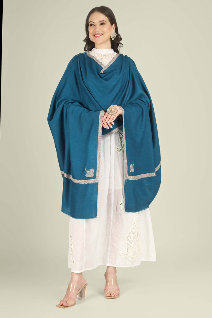 A woman modeling a teal blue shawl with silver embroidered borders over a white embroidered dress, standing against a solid light beige background.
    
      | pashmina shawls online | authentic Kashmiri pashmina shawl online | pure pashmina shawl online | original GI certified pashmina shawl online | luxury men's pashmina shawl online from Kashmir | where to buy online pure pashmina in India
    
    | GI Tag Certified - Government-verified authentic Kashmiri Pashmina
    | G20 Official Partner - Selected by India for G20 Summit gifting
    | Handicraft Registered - Official recognition of traditional craftsmanship
    | Certificate of Authenticity - Every purchase includes GI certification