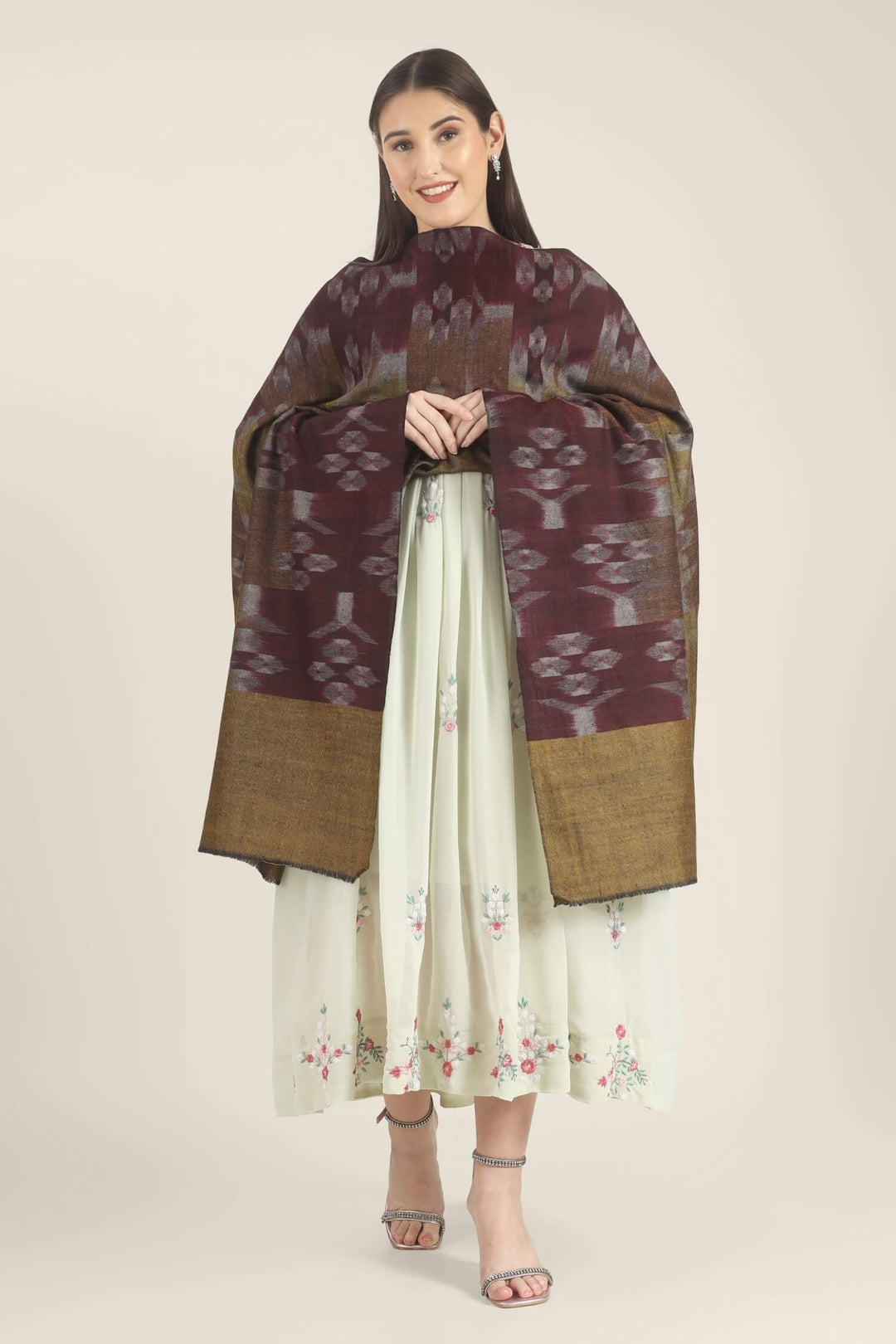 Model draped in a wine and mustard Pure Kashmiri Pashmina shawl with woven lilac-grey floral motifs over a pale green embroidered dress.
