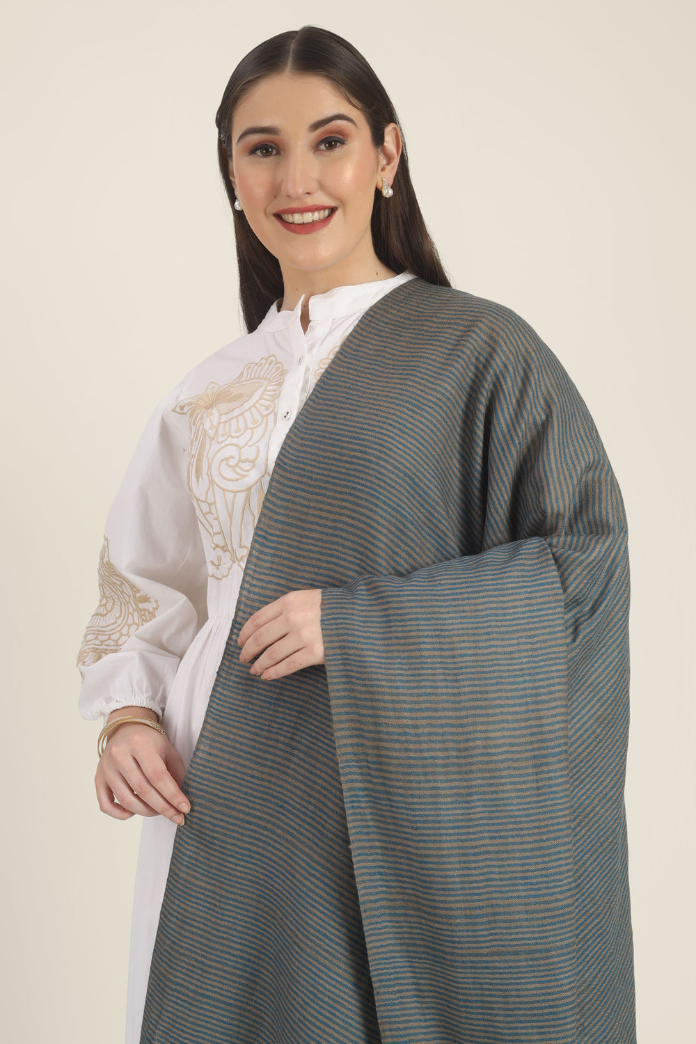 Model draped in a teal and taupe Pure Kashmiri Pashmina shawl with fine woven stripes and a wide plain teal border over a white embroidered dress.