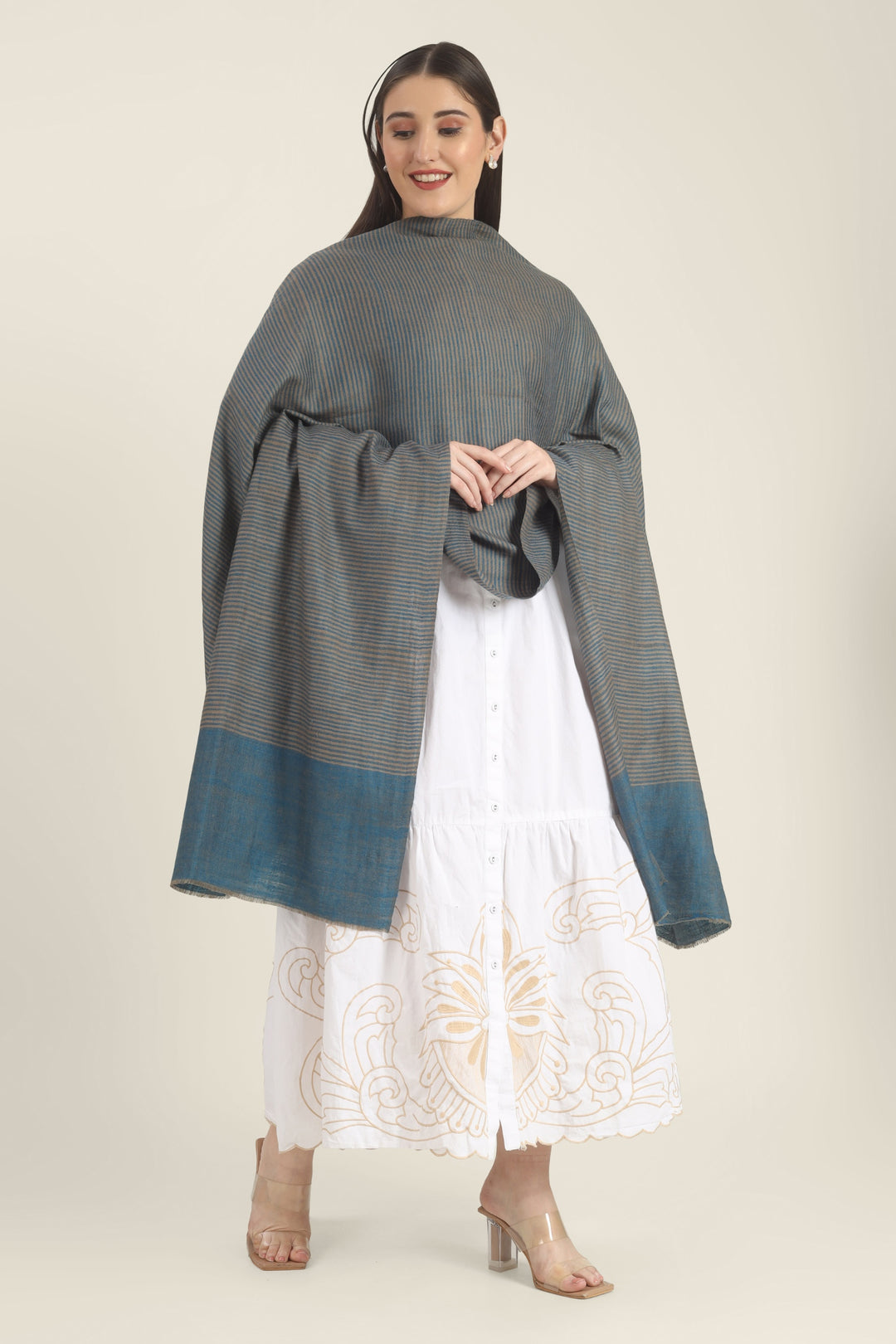 Model draped in a teal and taupe Pure Kashmiri Pashmina shawl with fine woven stripes and a wide plain teal border over a white embroidered dress.
