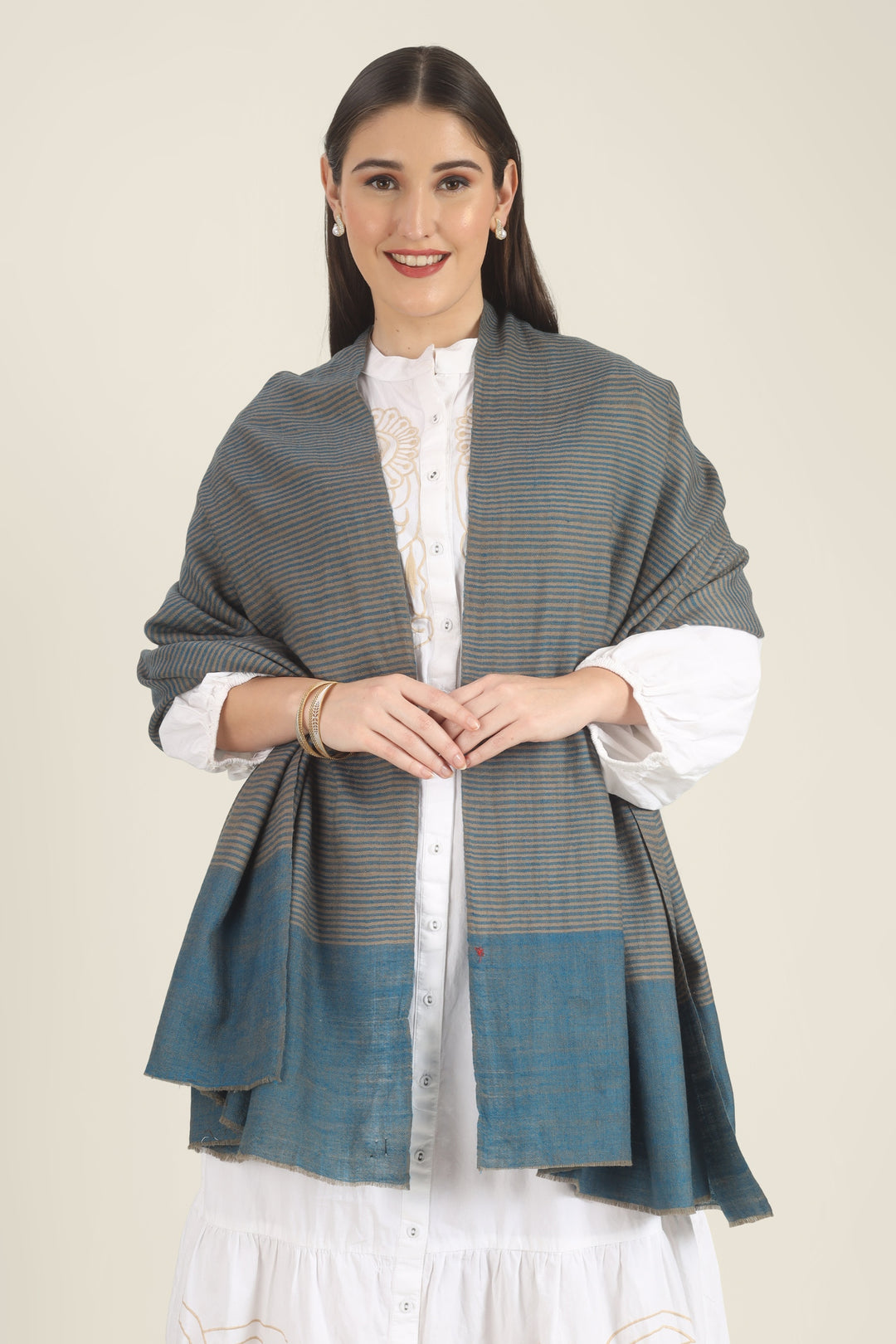 Model draped in a teal and taupe Pure Kashmiri Pashmina shawl with fine woven stripes and a wide plain teal border over a white embroidered dress.