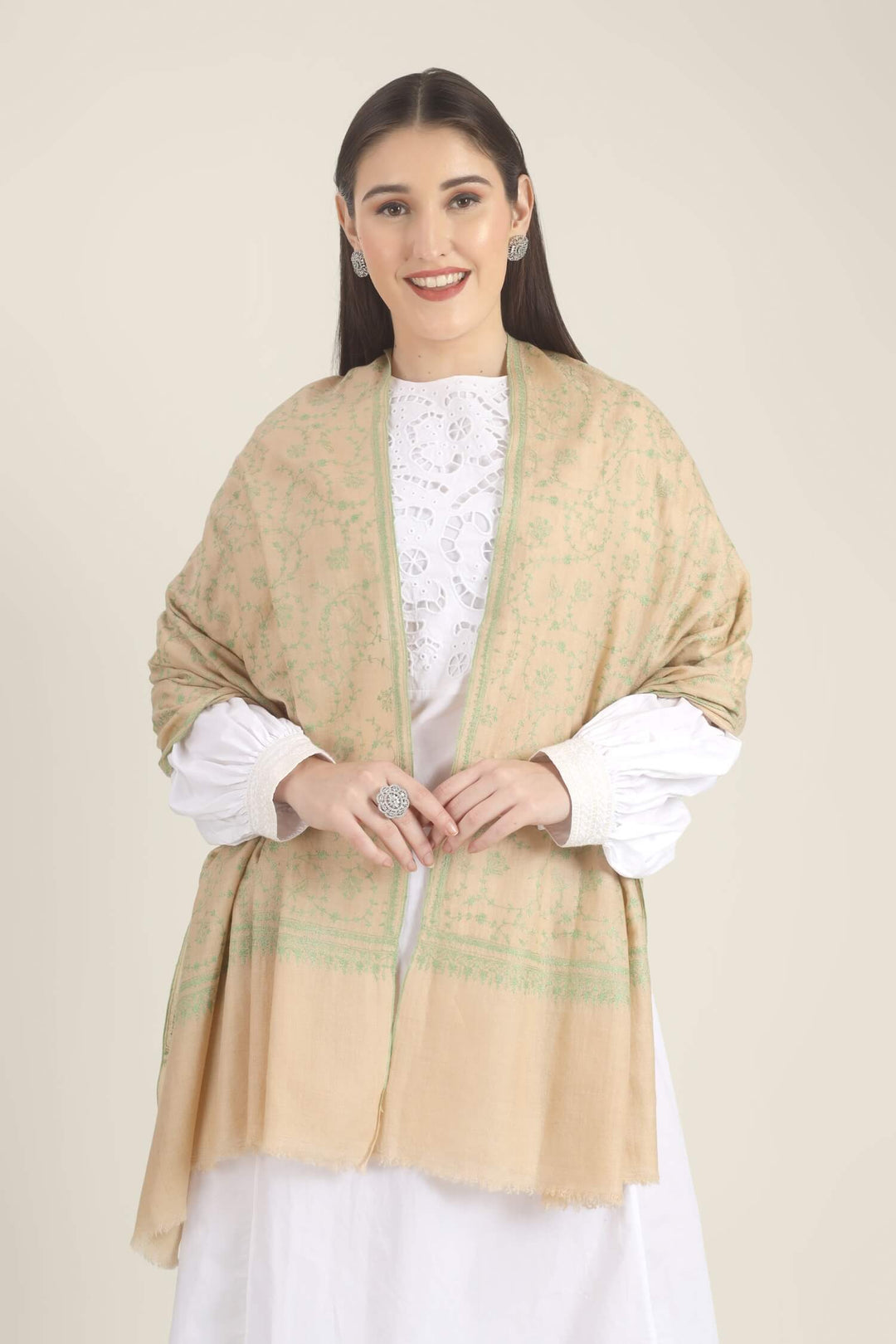 Model wearing a beige GI Kashmiri Pure Pashmina stole with soft green floral jaal Sozni embroidery over a white outfit.