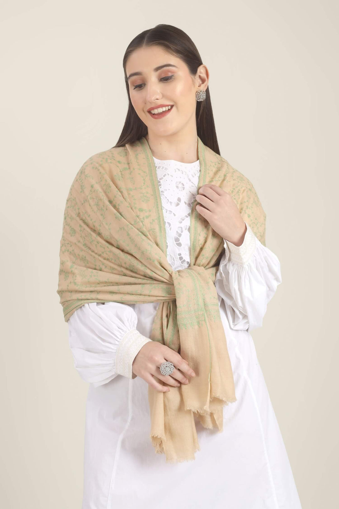 Model wearing a beige GI Kashmiri Pure Pashmina stole with soft green floral jaal Sozni embroidery over a white outfit.