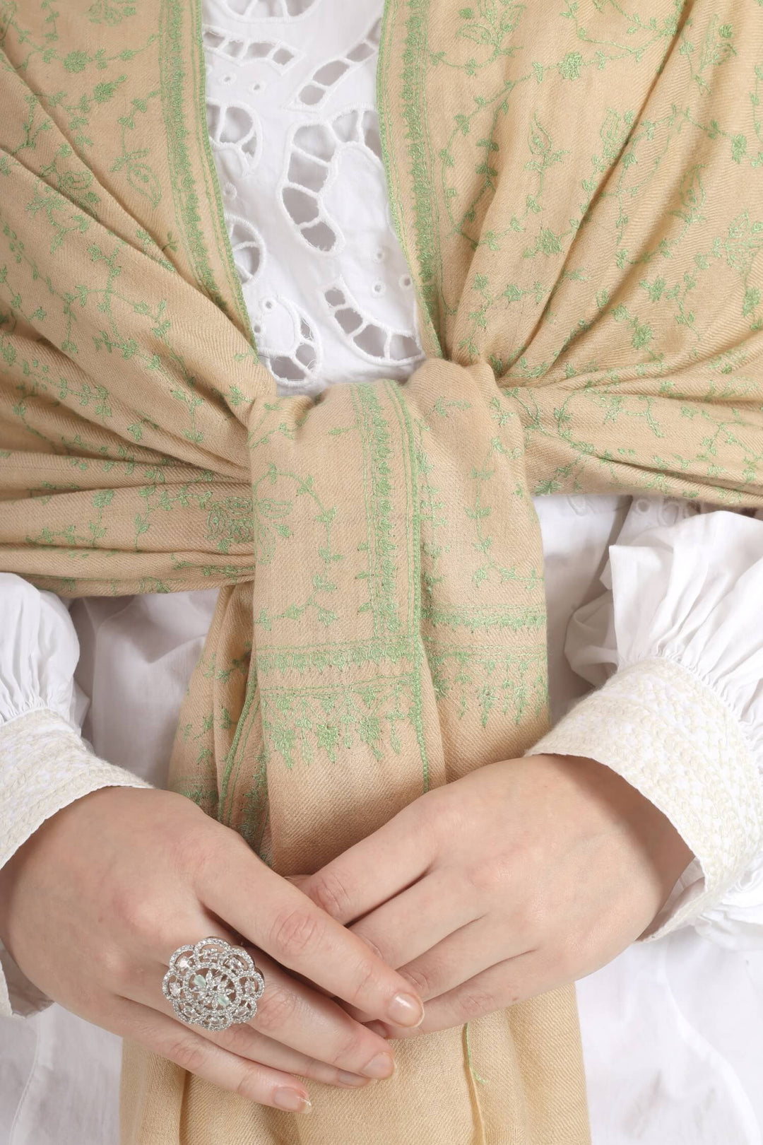 Model wearing a beige GI Kashmiri Pure Pashmina stole with soft green floral jaal Sozni embroidery over a white outfit.