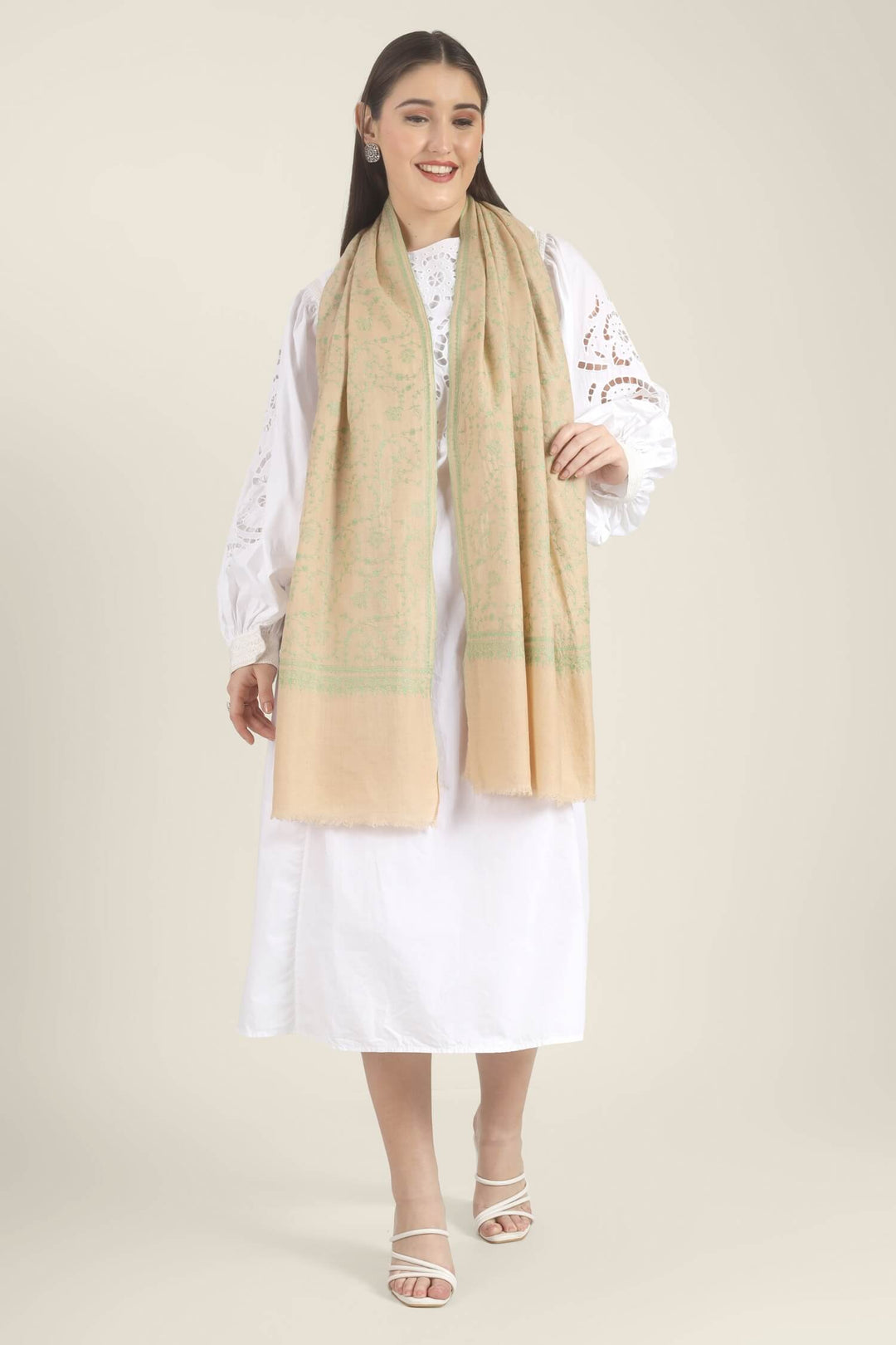 Model wearing a beige GI Kashmiri Pure Pashmina stole with soft green floral jaal Sozni embroidery over a white outfit.