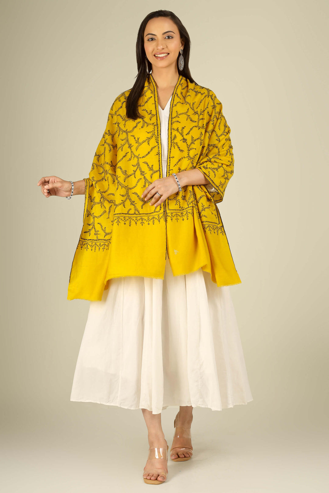 Yellow Kashmiri pure pashmina embroidered stole by Kepra, draped on smiling model in white dress, full-length front view for London winter styling