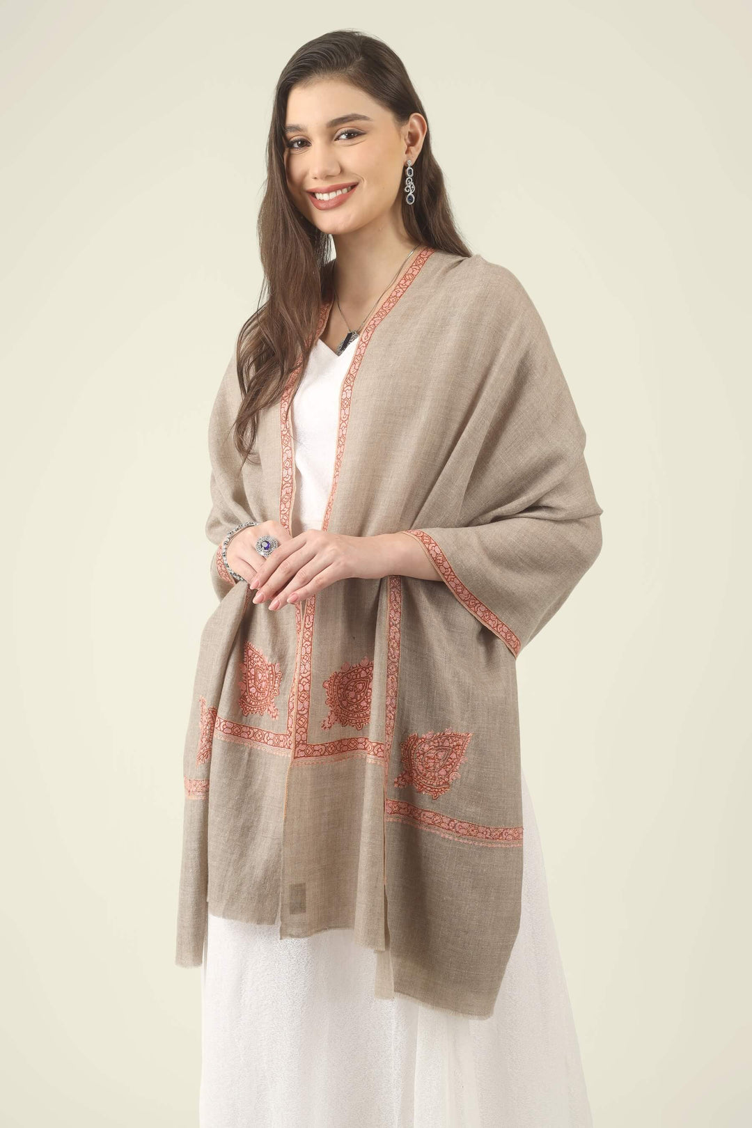 This Beige Pure Kashmiri Pashmina Paisley Embroidered Stole features a soft natural beige body decorated with richly worked paisley motifs and framed borders in rust, coral and pink.