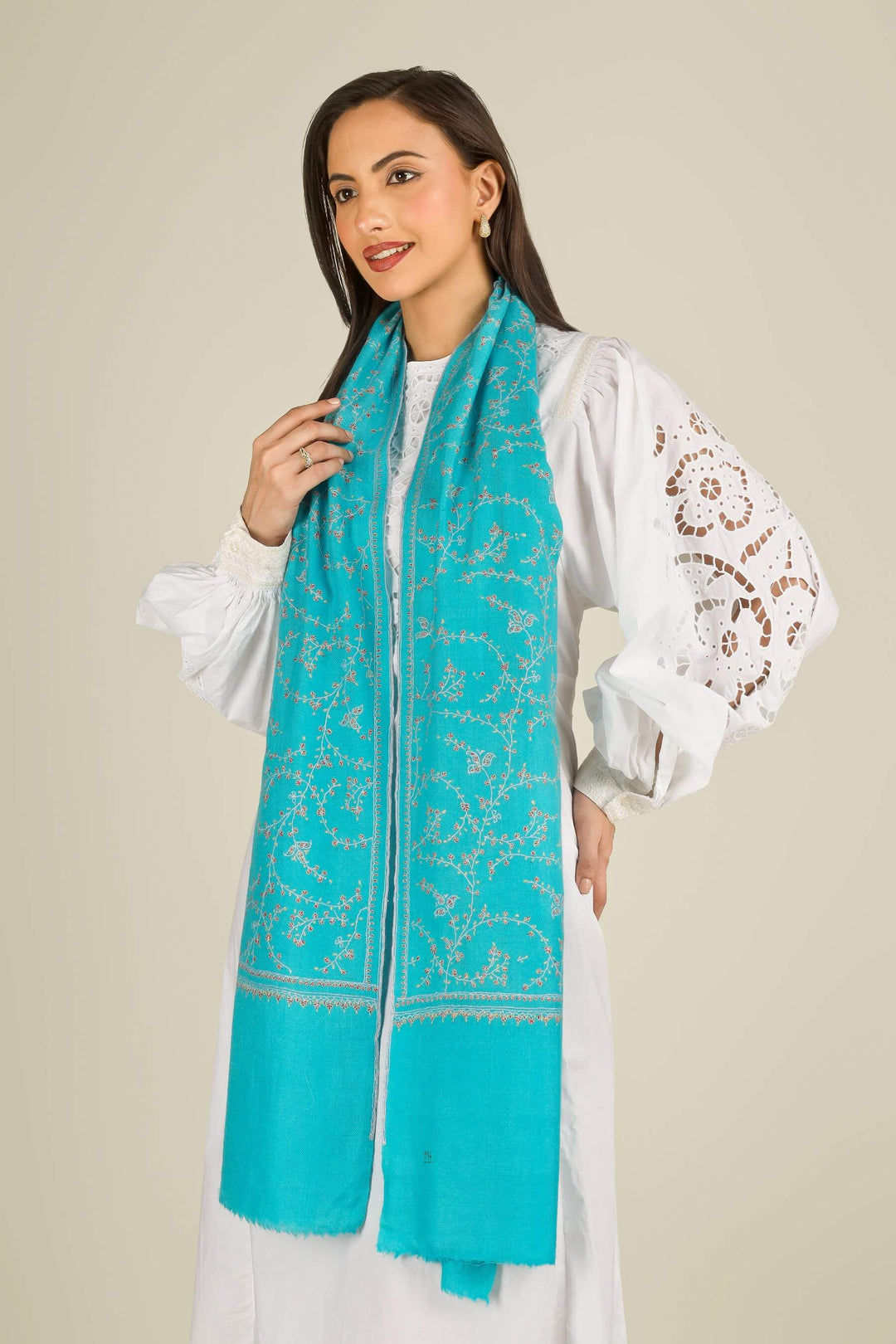 This GI Turquoise Kashmiri Pure Pashmina Embroidered Stole is a bright, refreshing accessory, handwoven in Kashmir and patterned with delicate all-over vines that frame the edges and flow softly along the length of the fabric.