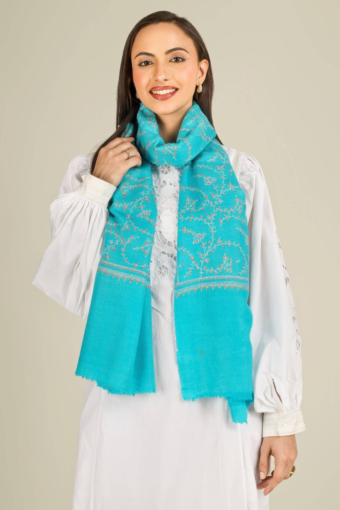 This GI Turquoise Kashmiri Pure Pashmina Embroidered Stole is a bright, refreshing accessory, handwoven in Kashmir and patterned with delicate all-over vines that frame the edges and flow softly along the length of the fabric.