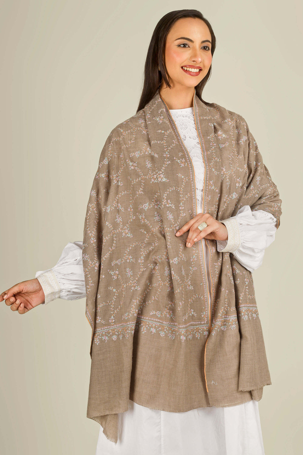 GI taupe Kashmiri pure pashmina embroidered stole by Kepra, draped over white dress on smiling model, front view