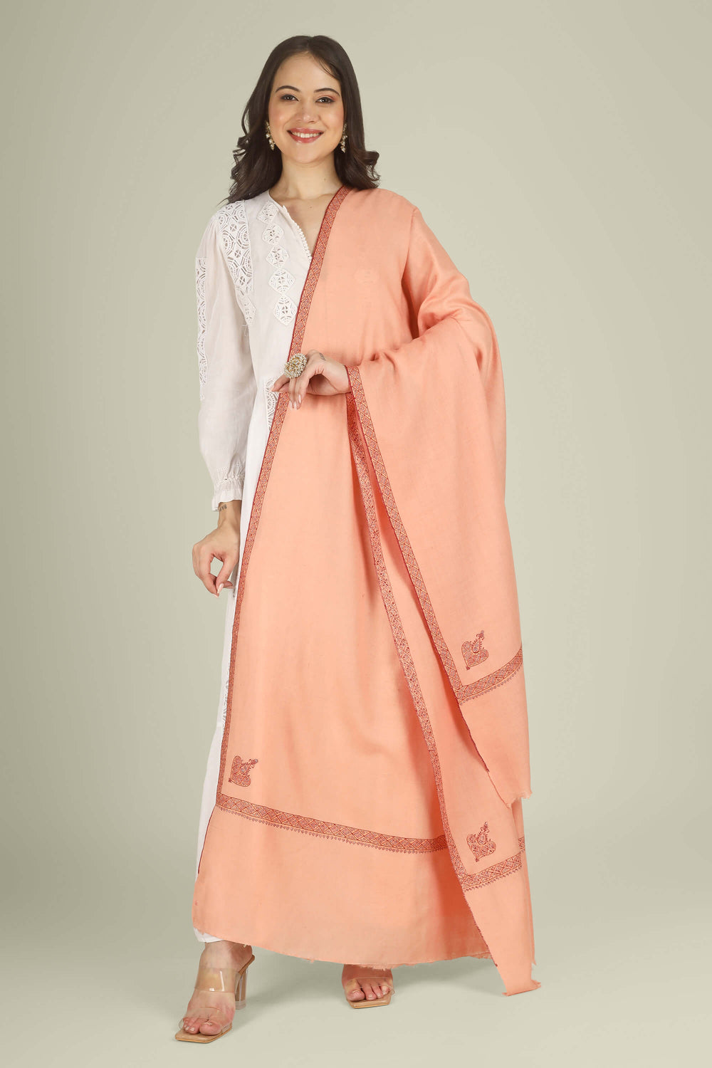 This Peach GI Kashmiri Pure Pashmina Raiha Hashidaar Shawl comes in a soft peach base highlighted with a geometric hashidaar border and a single ornate corner motif, giving a clean, modern look with a touch of traditional detail.
